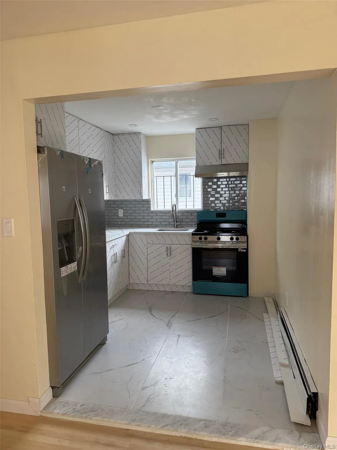 Kitchen featuring decorative backsplash, appliances with stainless steel finishes, and a baseboard heating unit Kitchen featuring decorative backsplash, appliances with stainless steel finishes, and a baseboard heating unit