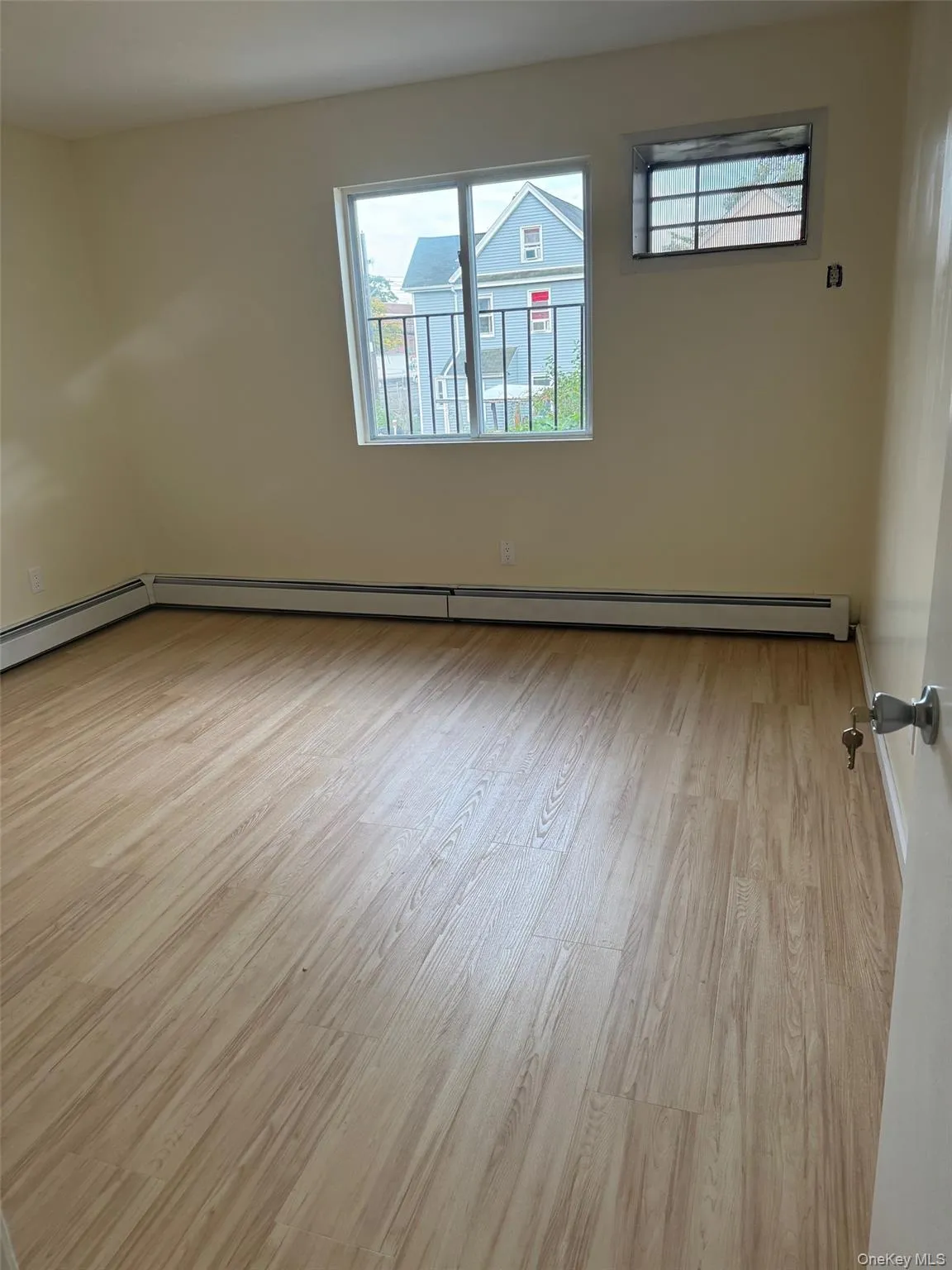 Empty room featuring light wood-style floors, healthy amount of natural light, and a baseboard radiator Empty room featuring light wood-style floors, healthy amount of natural light, and a baseboard radiator
