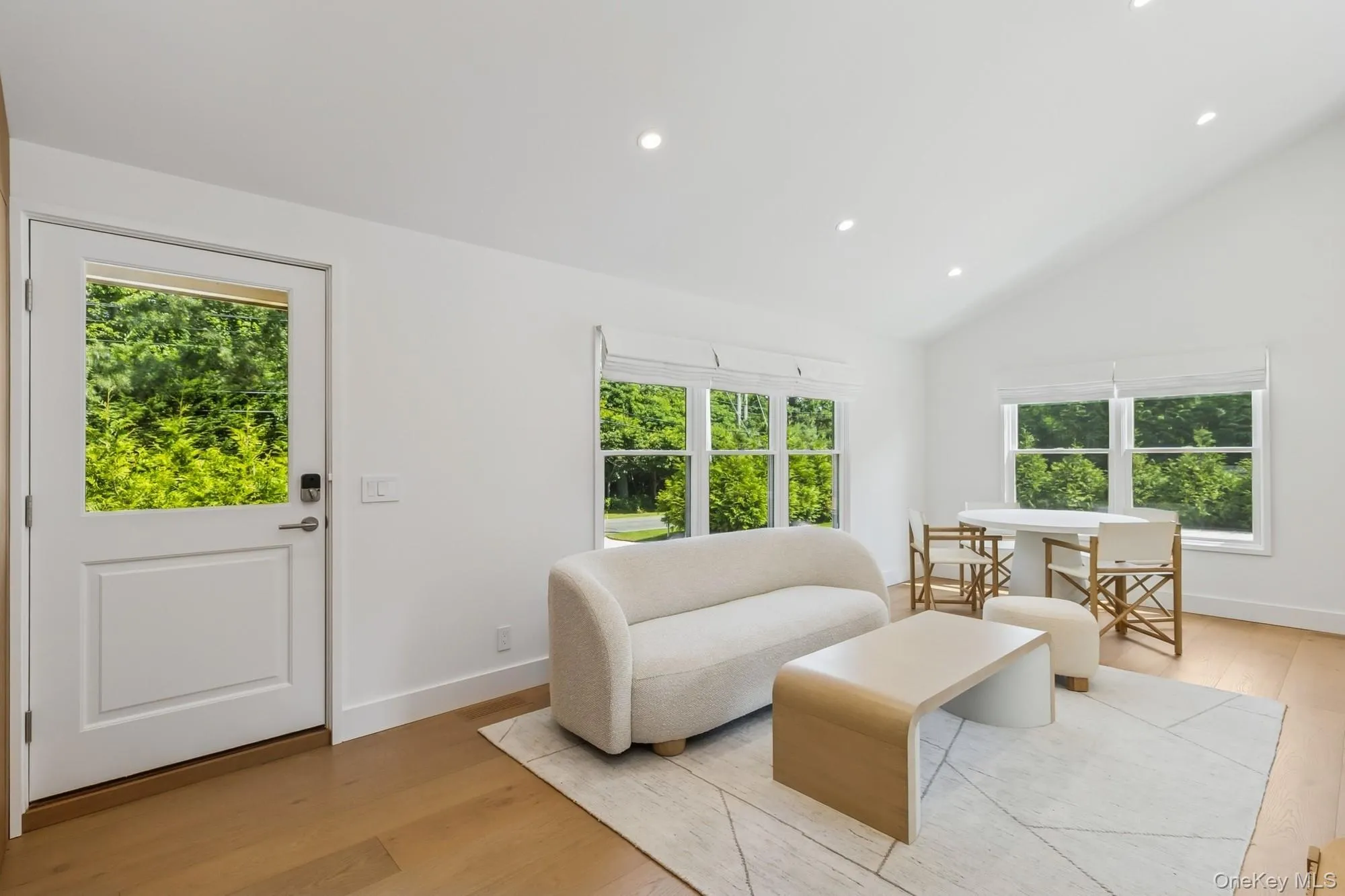 Living room with recessed lighting, plenty of natural light, light wood-style floors, and high vaulted ceiling Living room with recessed lighting, plenty of natural light, light wood-style floors, and high vaulted ceiling