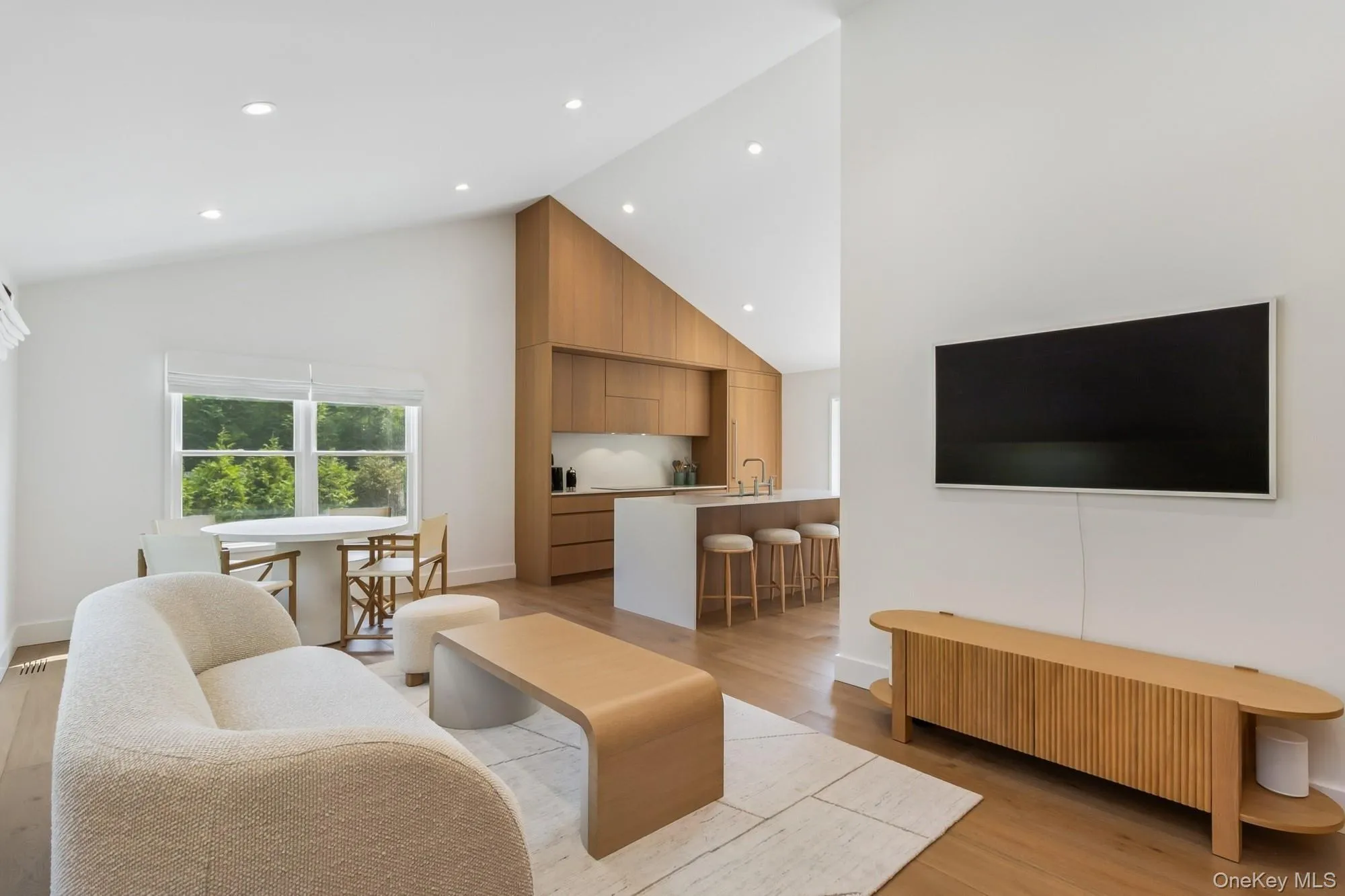Living room with high vaulted ceiling, light wood-style floors, and recessed lighting Living room with high vaulted ceiling, light wood-style floors, and recessed lighting