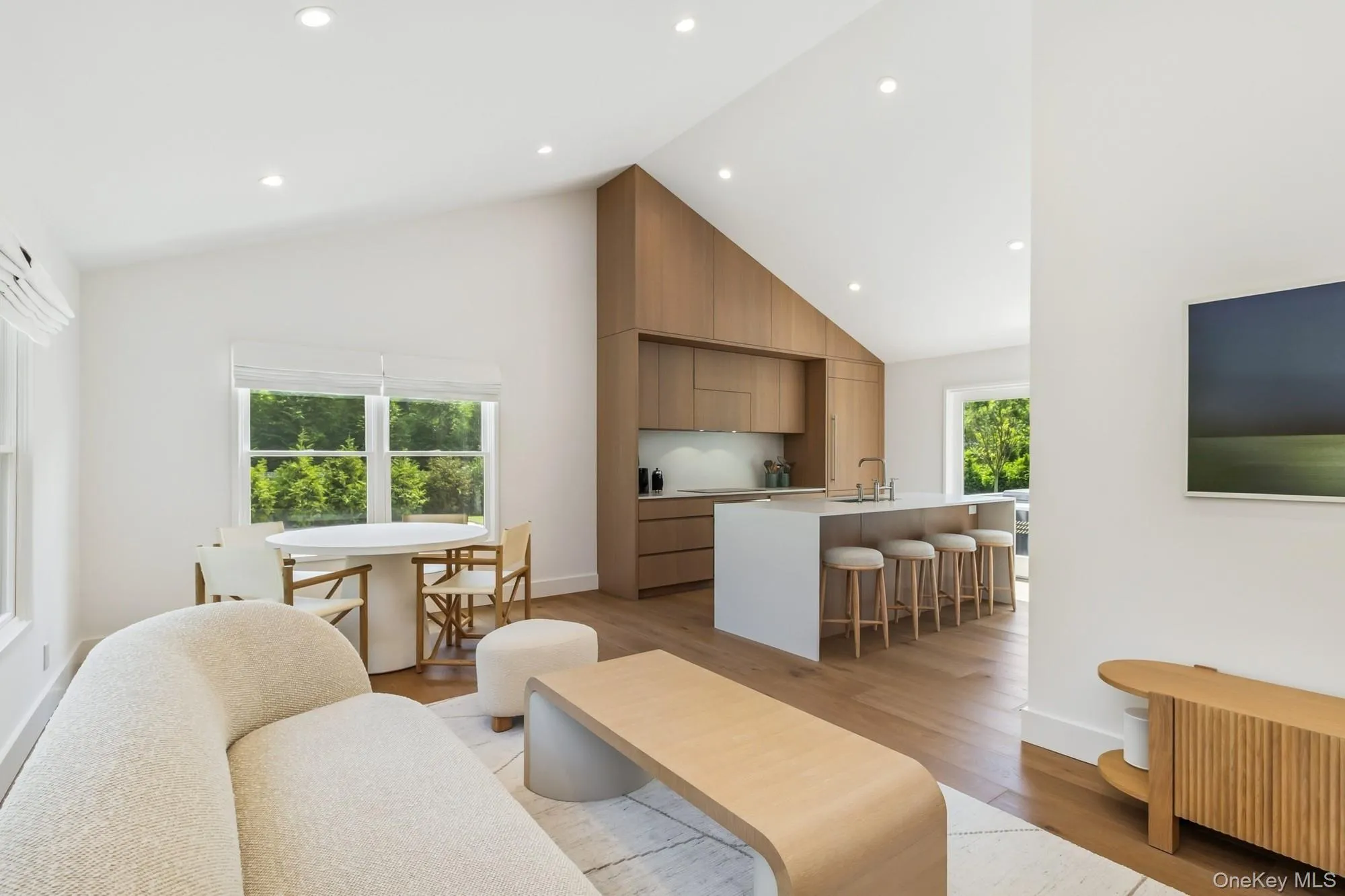Living area with high vaulted ceiling, light wood-style floors, and recessed lighting Living area with high vaulted ceiling, light wood-style floors, and recessed lighting
