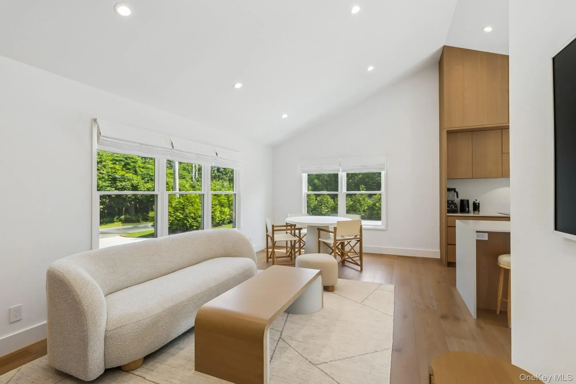 Living room with light wood-style floors, recessed lighting, and high vaulted ceiling Living room with light wood-style floors, recessed lighting, and high vaulted ceiling