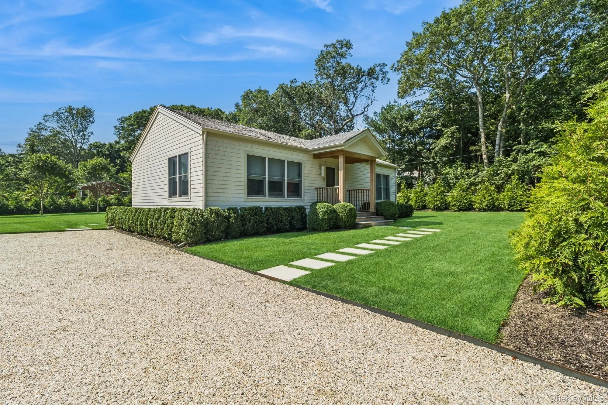 View of side of home with a lawn, gravel driveway, and covered porch View of side of home with a lawn, gravel driveway, and covered porch