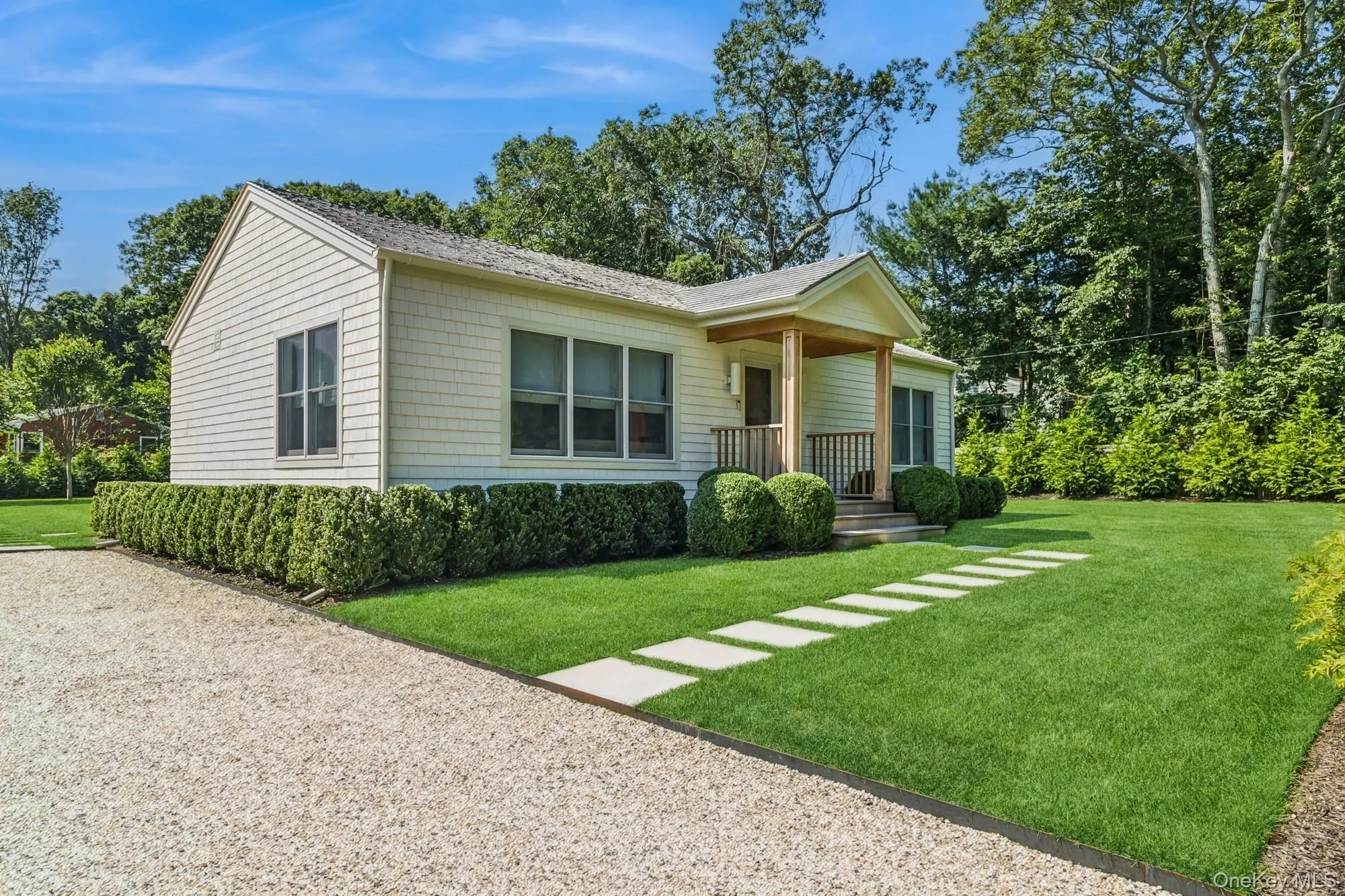 View of front of house with a front lawn, a porch, and view of wooded area View of front of house with a front lawn, a porch, and view of wooded area