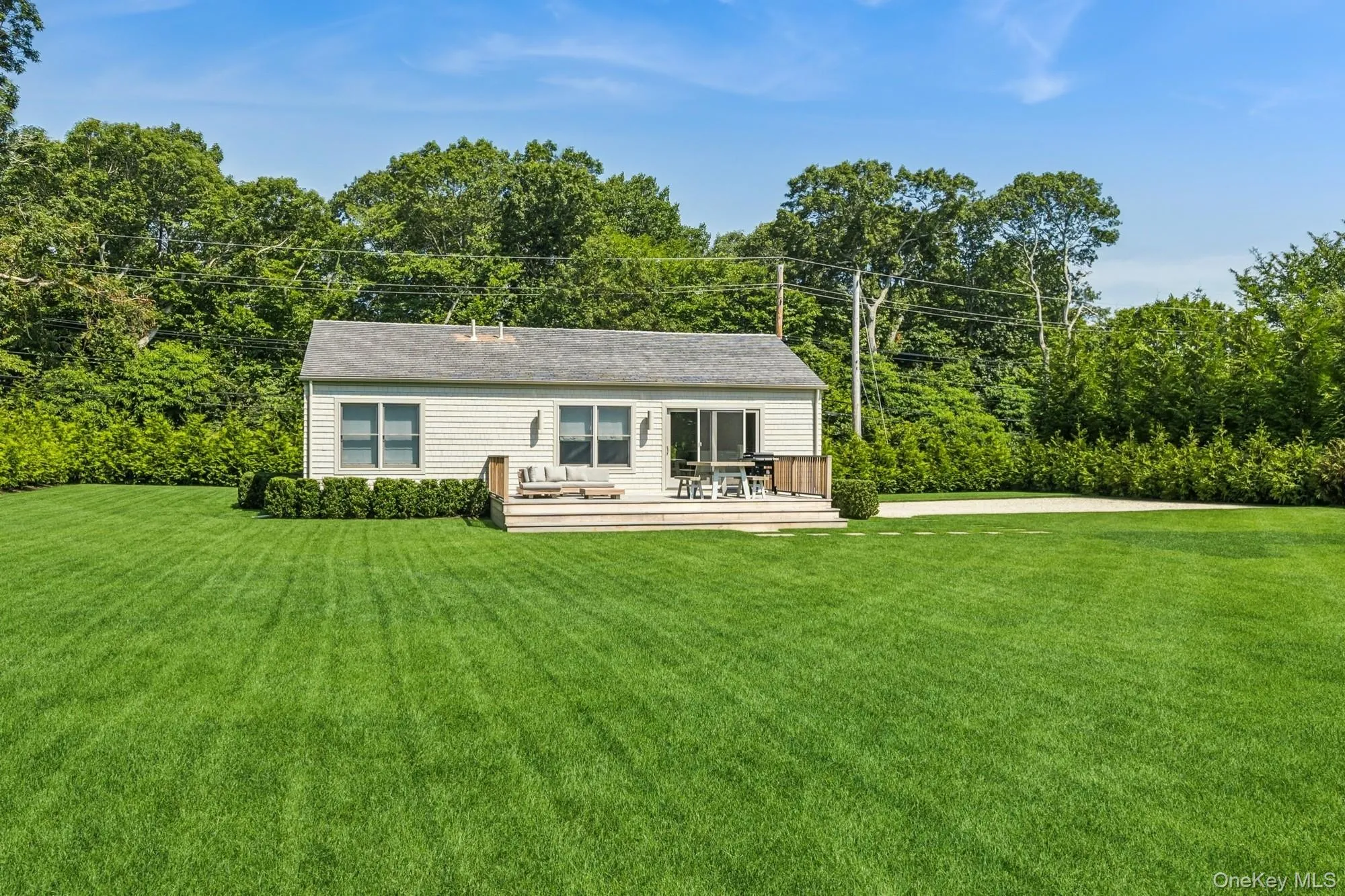Back of property with a wooden deck, a lawn, and view of scattered trees Back of property with a wooden deck, a lawn, and view of scattered trees