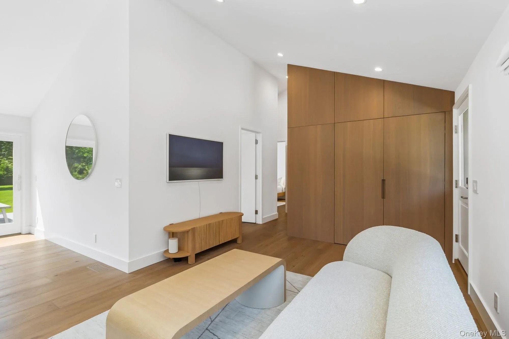 Living room with high vaulted ceiling, light wood-style flooring, and recessed lighting Living room with high vaulted ceiling, light wood-style flooring, and recessed lighting