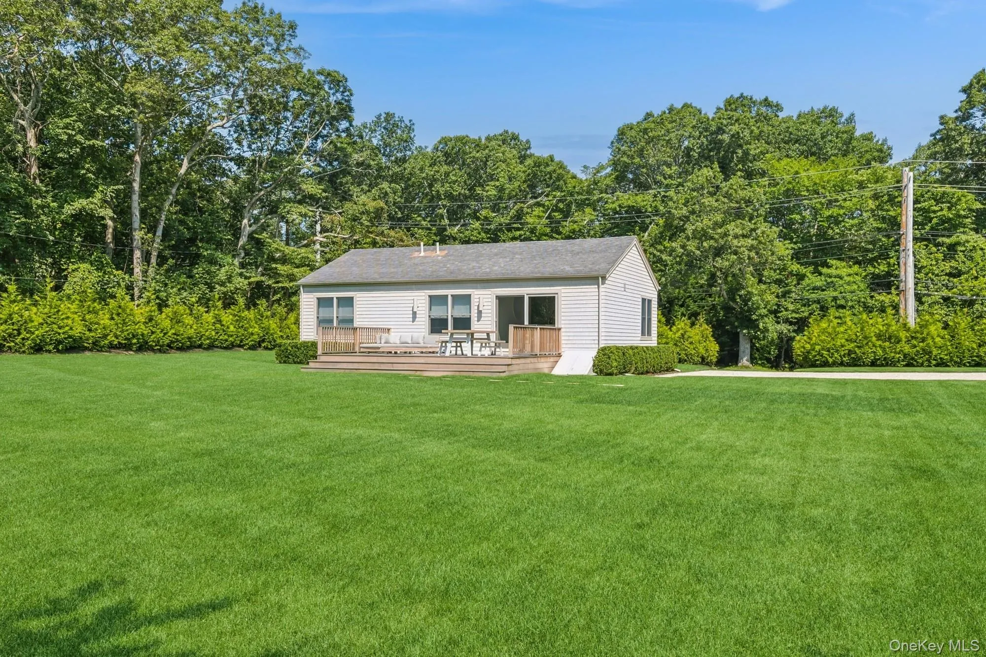 Rear view of house featuring a yard, a deck, and view of wooded area Rear view of house featuring a yard, a deck, and view of wooded area