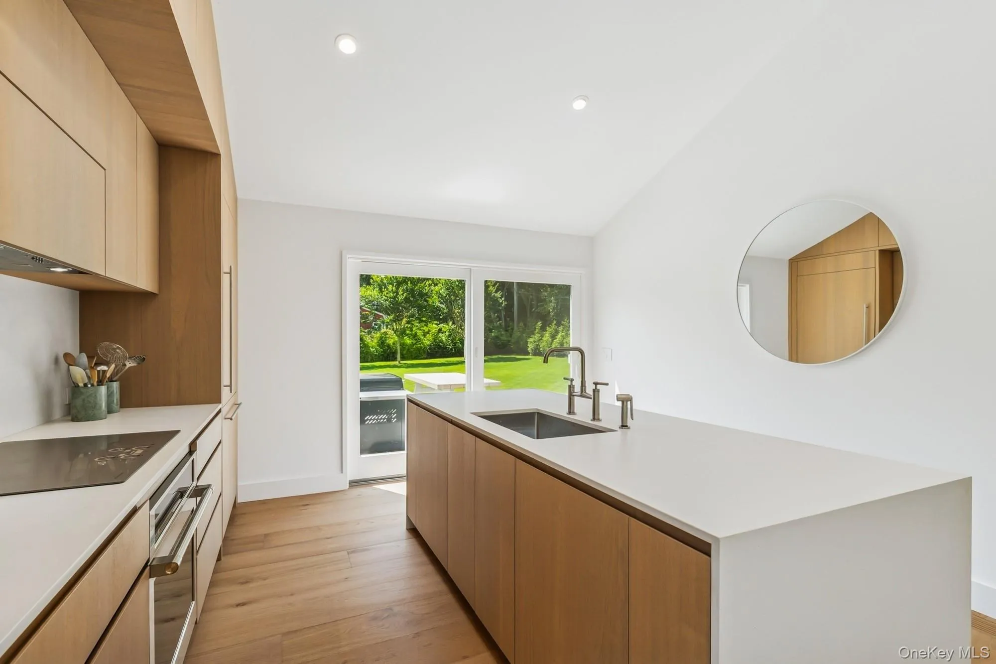 Kitchen with modern cabinets, light wood-style floors, light brown cabinetry, an island with sink, and recessed lighting Kitchen with modern cabinets, light wood-style floors, light brown cabinetry, an island with sink, and recessed lighting