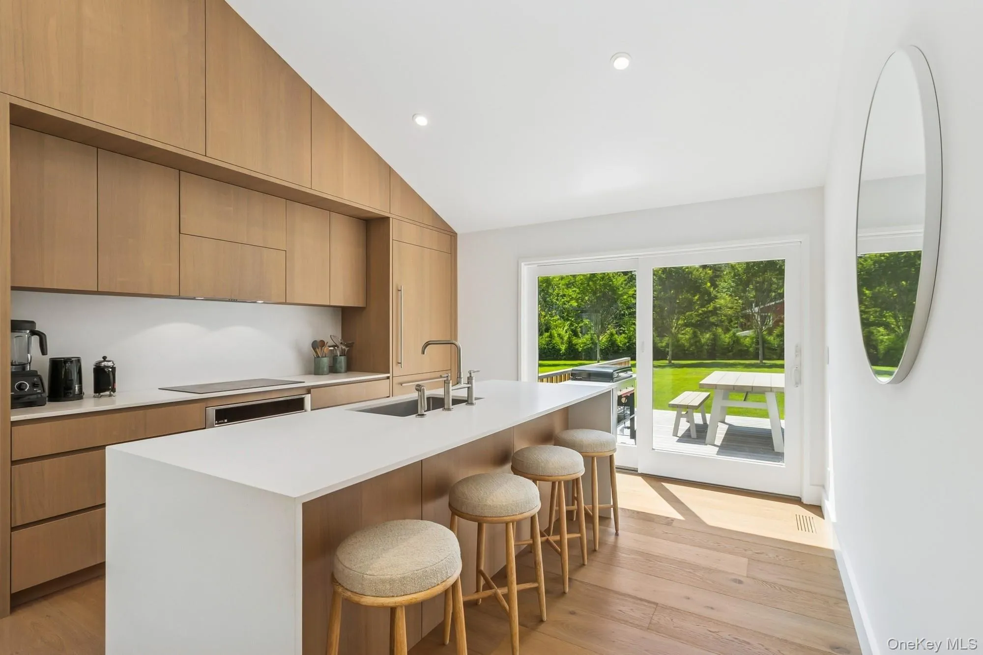 Kitchen with light wood-style flooring, a breakfast bar, modern cabinets, recessed lighting, and light stone countertops Kitchen with light wood-style flooring, a breakfast bar, modern cabinets, recessed lighting, and light stone countertops