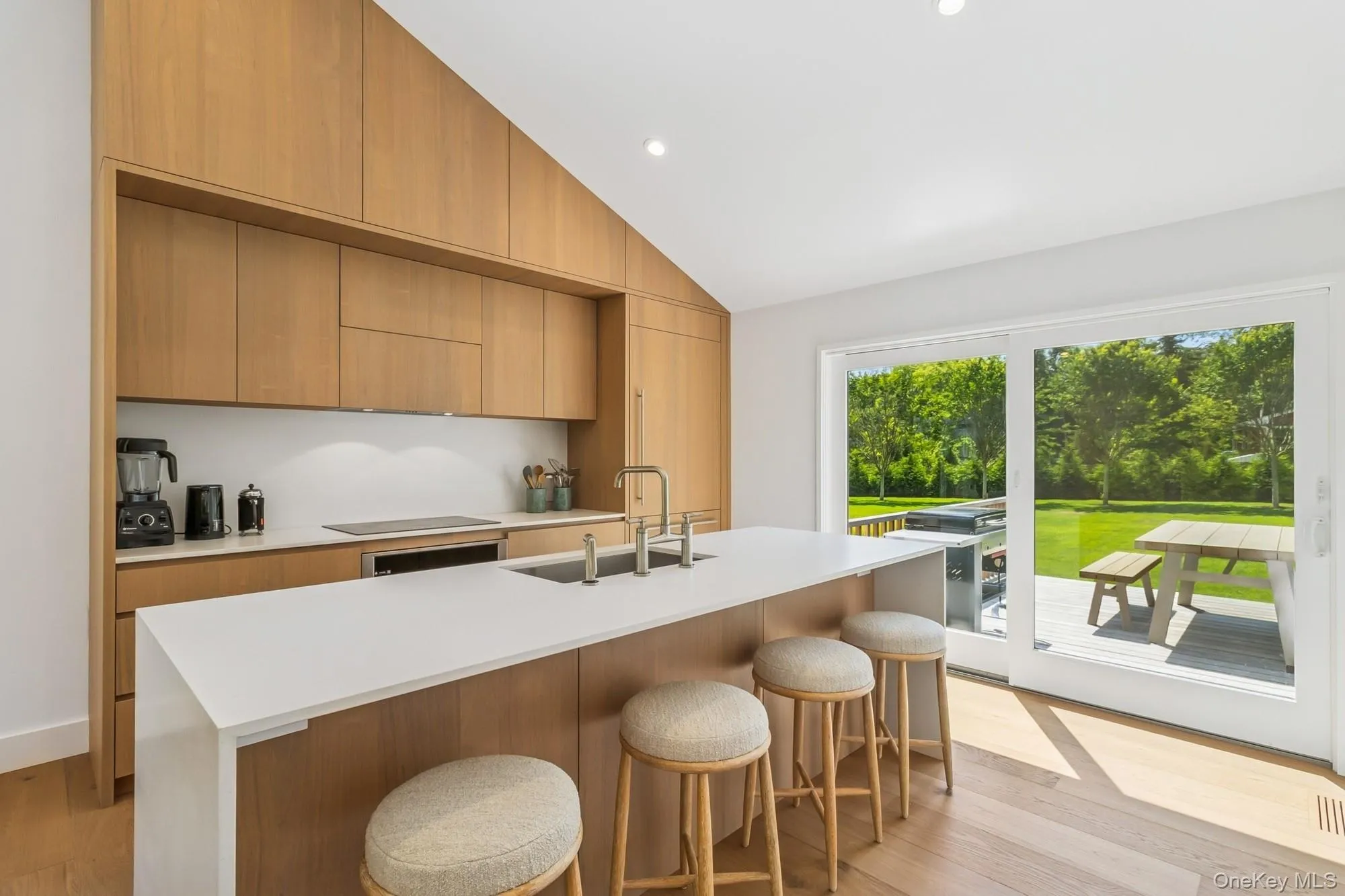 Kitchen with modern cabinets, a kitchen bar, light wood finished floors, vaulted ceiling, and recessed lighting Kitchen with modern cabinets, a kitchen bar, light wood finished floors, vaulted ceiling, and recessed lighting