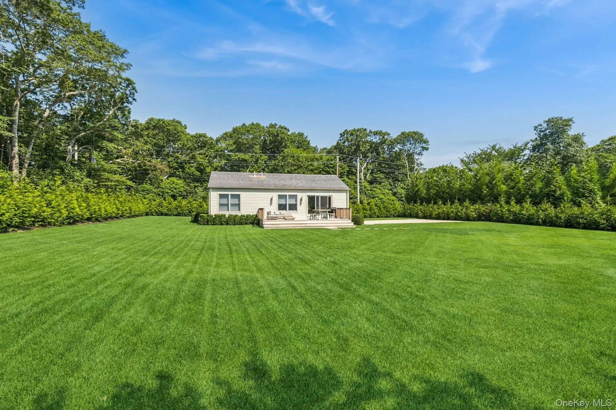 View of grassy yard with a deck and view of scattered trees View of grassy yard with a deck and view of scattered trees