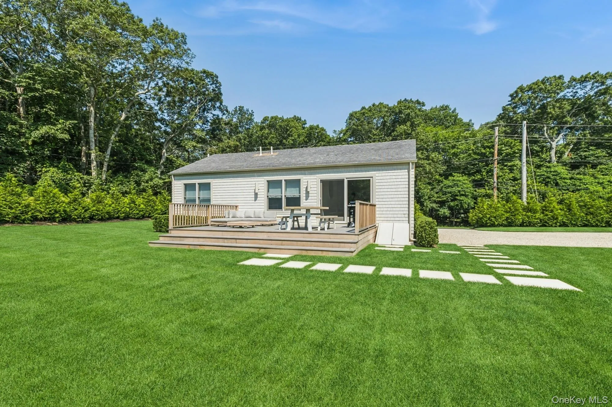 Back of house featuring a yard, a wooden deck, and view of wooded area Back of house featuring a yard, a wooden deck, and view of wooded area