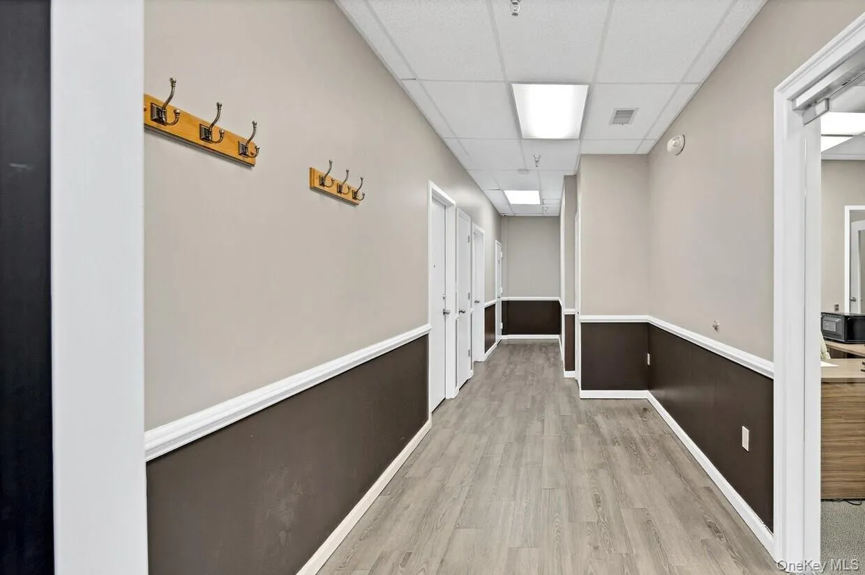 Corridor featuring a paneled ceiling and light wood finished floors Corridor featuring a paneled ceiling and light wood finished floors