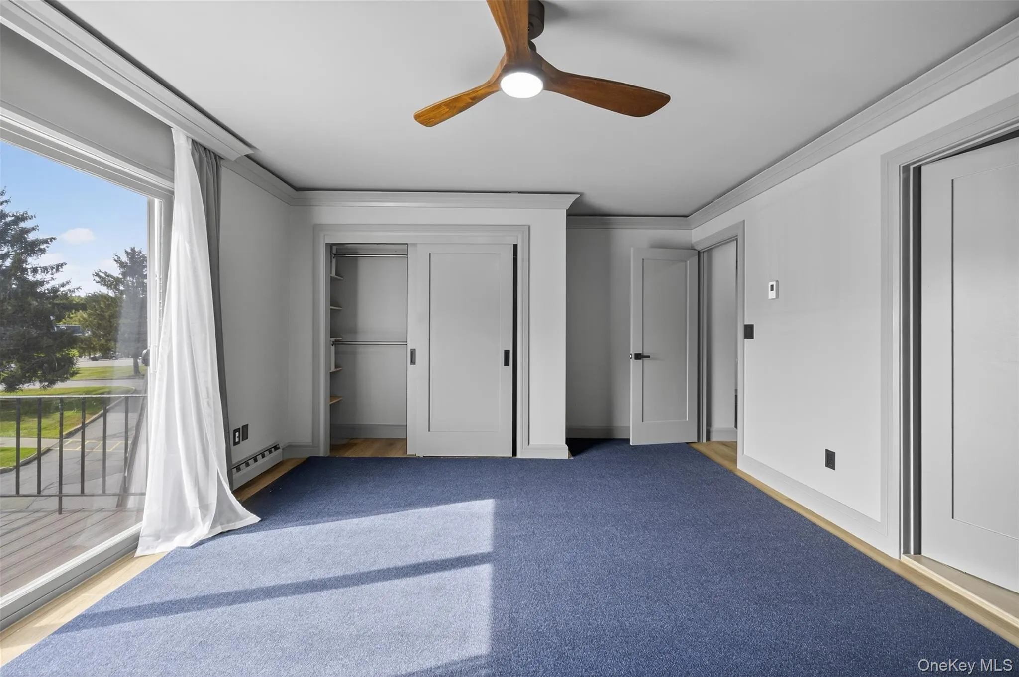 Unfurnished bedroom with access to outside, a closet, ornamental molding, ceiling fan, and a baseboard heating unit Unfurnished bedroom with access to outside, a closet, ornamental molding, ceiling fan, and a baseboard heating unit