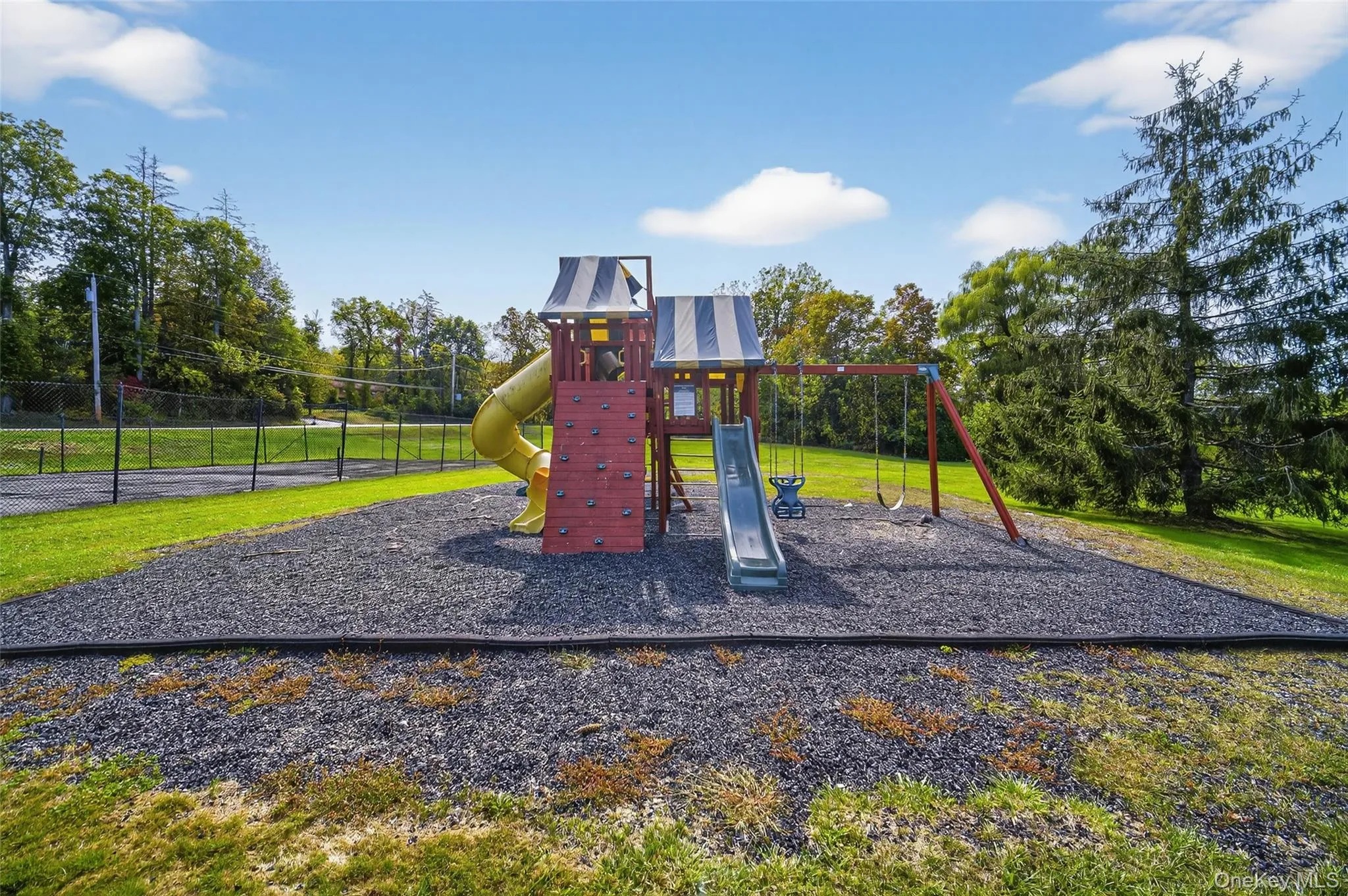 Community playground featuring view of wooded area and a yard Community playground featuring view of wooded area and a yard