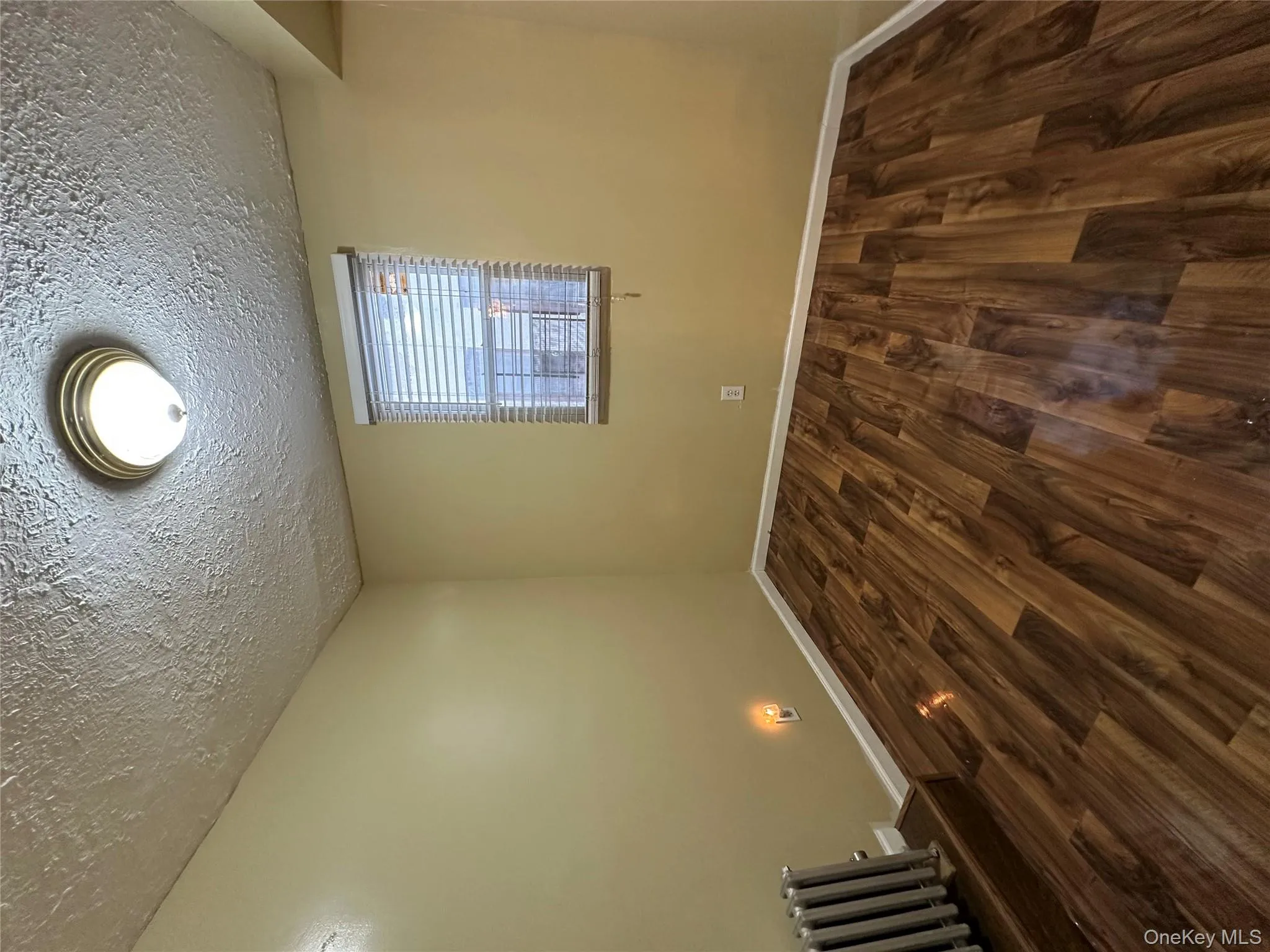 Spare room featuring radiator heating unit, dark wood-type flooring, and a textured ceiling Spare room featuring radiator heating unit, dark wood-type flooring, and a textured ceiling