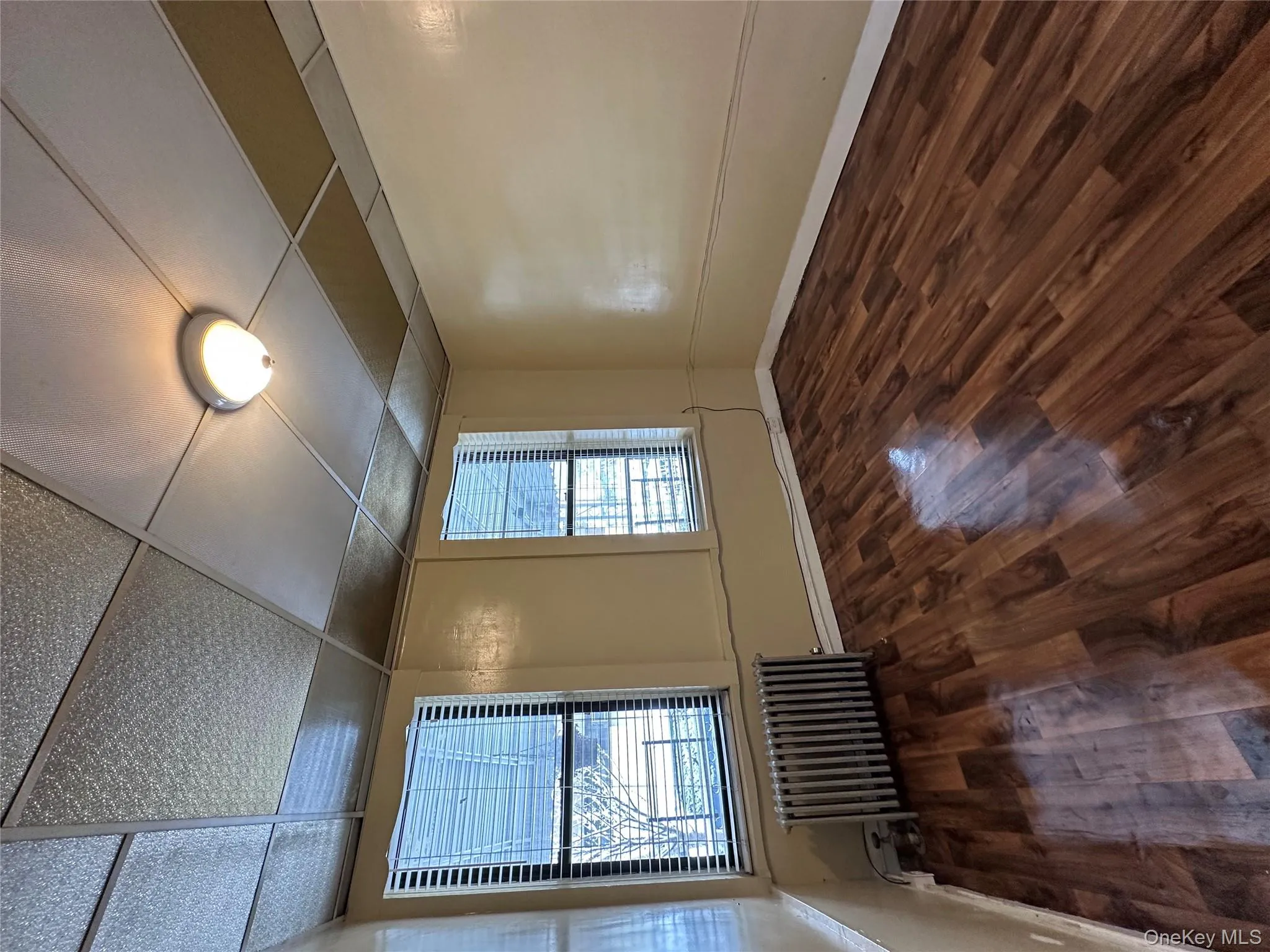 Larger bedroom with radiator, dark wood-style flooring, and a paneled ceiling Larger bedroom with radiator, dark wood-style flooring, and a paneled ceiling