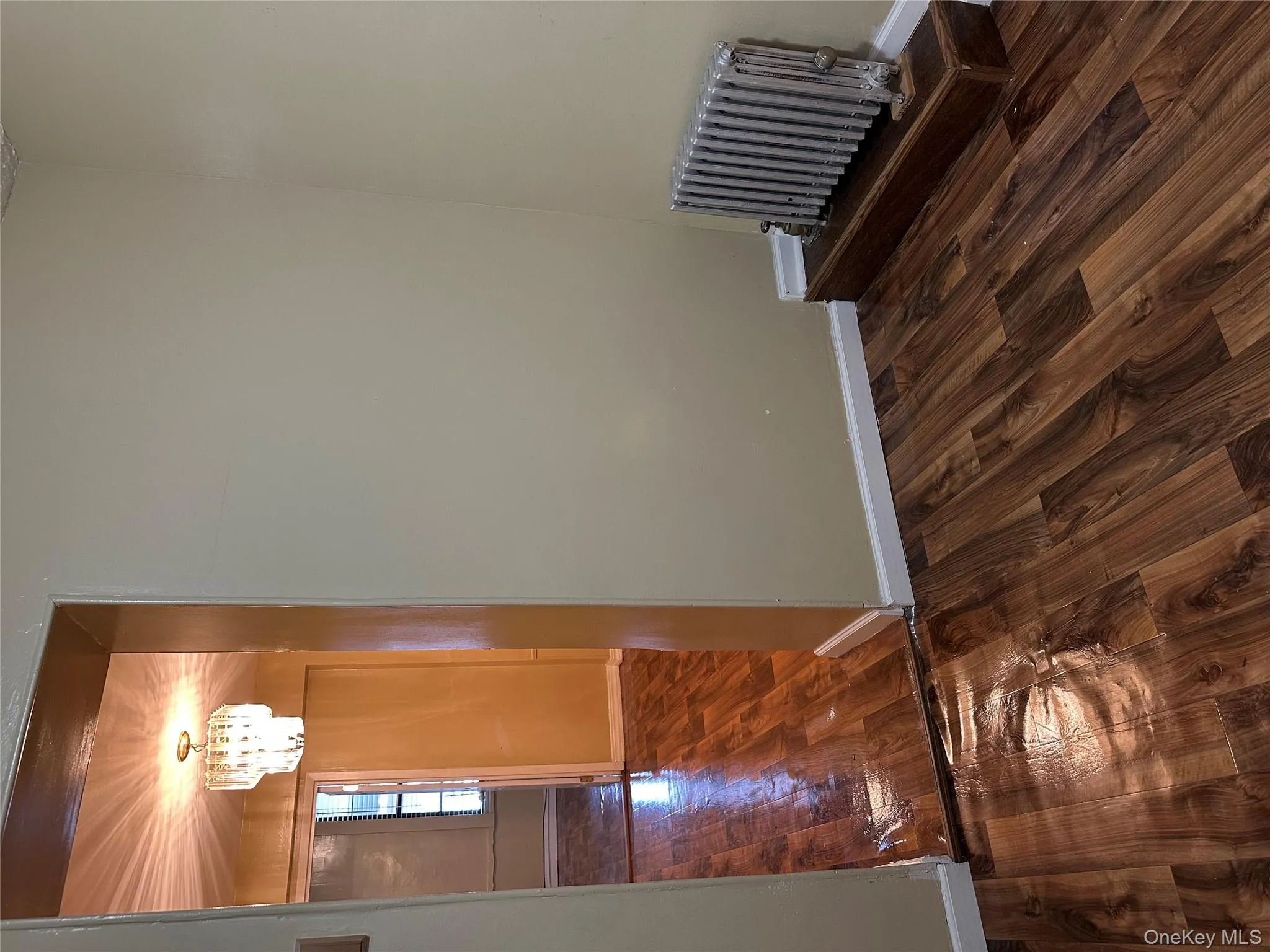 Empty room with dark wood-type flooring, radiator heating unit, and a chandelier Empty room with dark wood-type flooring, radiator heating unit, and a chandelier