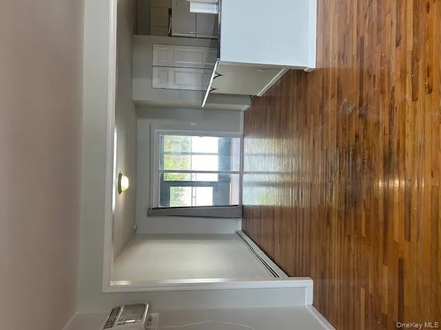 Spare room featuring dark wood-style flooring, a baseboard heating unit, and a wall mounted AC Spare room featuring dark wood-style flooring, a baseboard heating unit, and a wall mounted AC