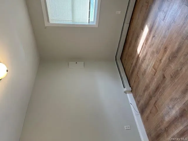 Spare room featuring light wood finished floors and a baseboard radiator Spare room featuring light wood finished floors and a baseboard radiator