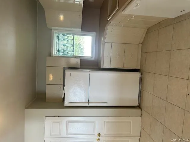 Kitchen featuring freestanding refrigerator, dishwasher, light tile patterned floors, and light countertops Kitchen featuring freestanding refrigerator, dishwasher, light tile patterned floors, and light countertops