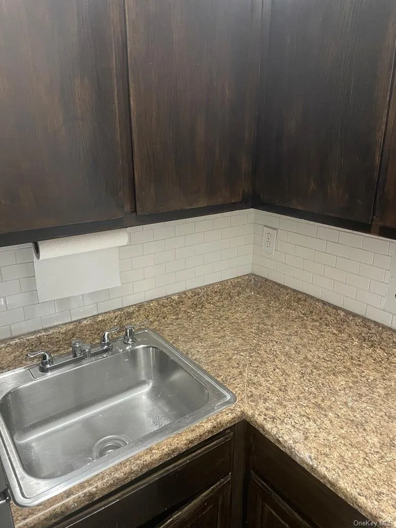 Kitchen view of dark brown cabinets, decorative backsplash, and light stone countertops Kitchen view of dark brown cabinets, decorative backsplash, and light stone countertops