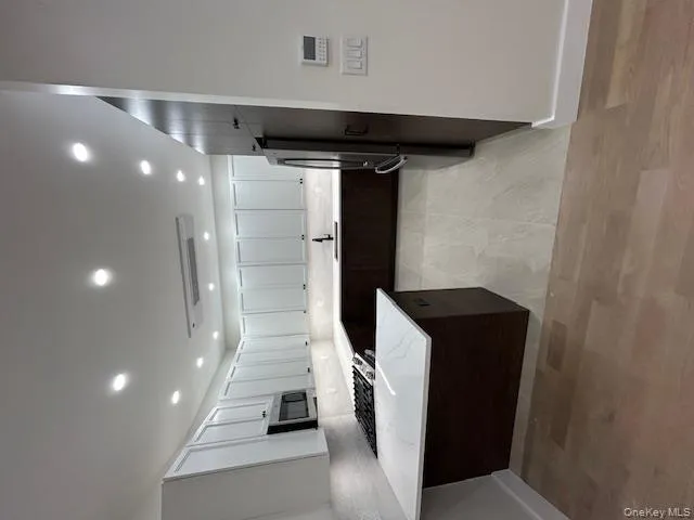 Kitchen with dark brown cabinets, fridge, tasteful backsplash, light stone countertops, and recessed lighting Kitchen with dark brown cabinets, fridge, tasteful backsplash, light stone countertops, and recessed lighting