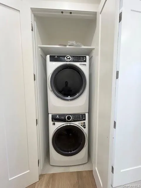 Laundry room featuring light wood-style floors and estacked washer and dryer Laundry room featuring light wood-style floors and estacked washer and dryer