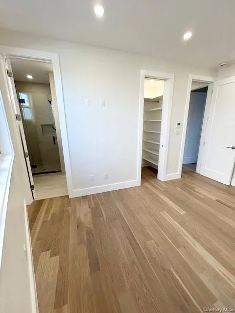 Unfurnished bedroom with recessed lighting, light wood-type flooring, and a walk in closet Unfurnished bedroom with recessed lighting, light wood-type flooring, and a walk in closet