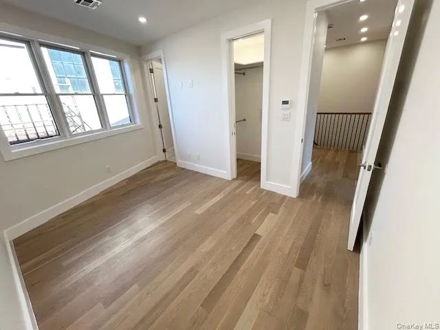 Unfurnished bedroom with a walk in closet, light wood-type flooring, and recessed lighting Unfurnished bedroom with a walk in closet, light wood-type flooring, and recessed lighting