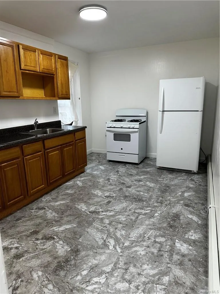 Kitchen with range, sink, refrigerator, and dark stone counters Kitchen with range, sink, refrigerator, and dark stone counters