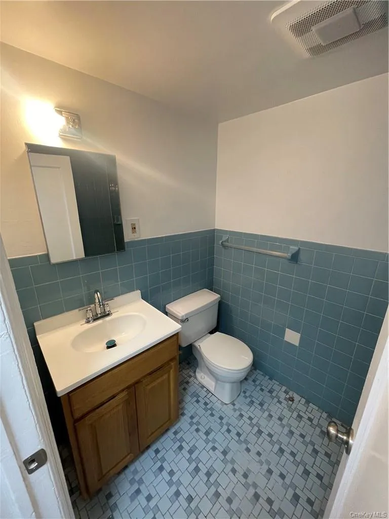 Bathroom with tile walls, backsplash, toilet, and vanity Bathroom with tile walls, backsplash, toilet, and vanity