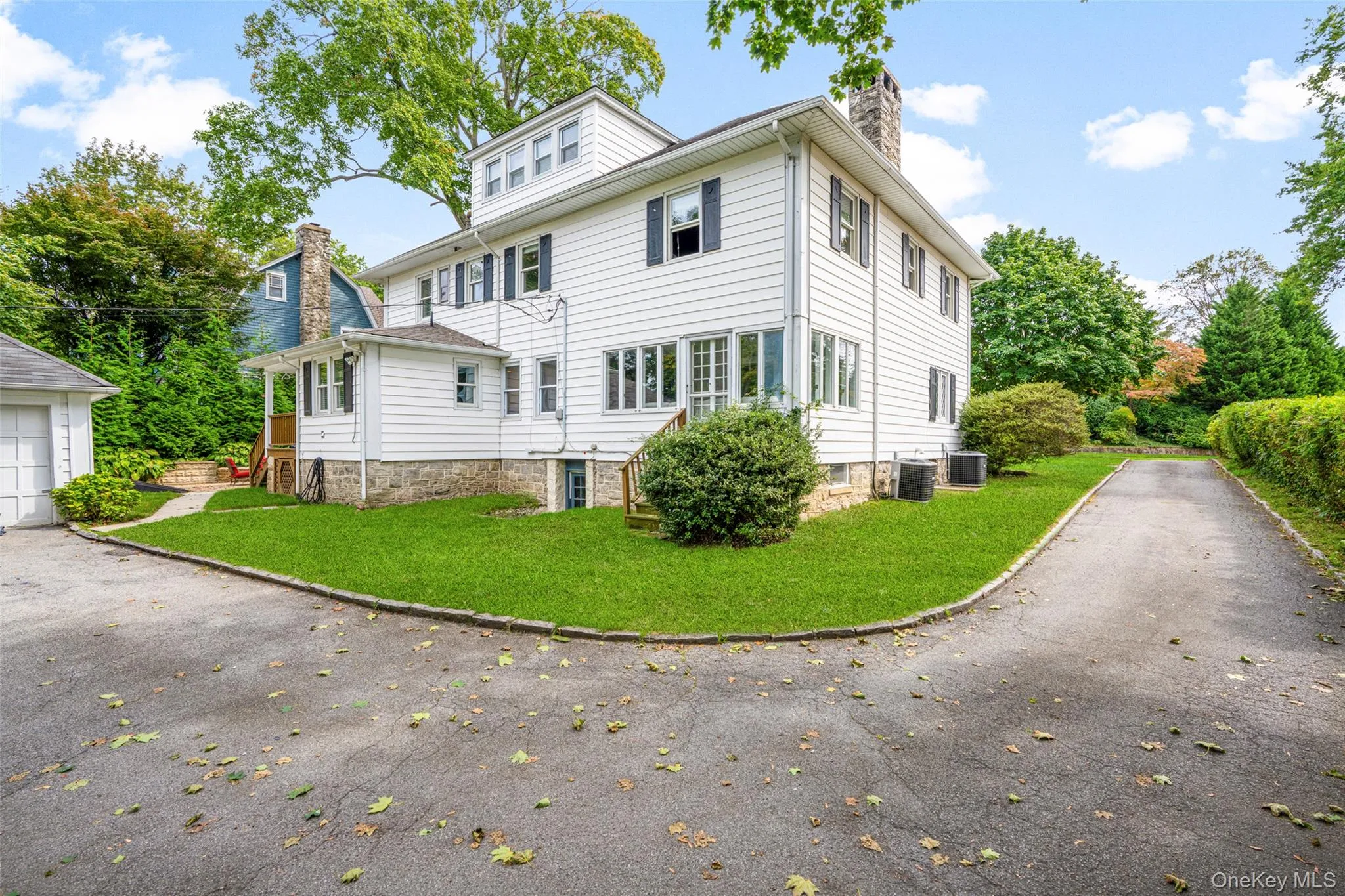 Rear view of house with a chimney, asphalt driveway, and a lawn Rear view of house with a chimney, asphalt driveway, and a lawn