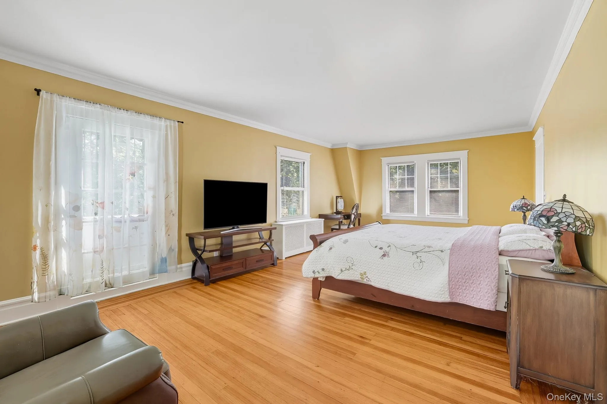 Primary bedroom featuring light wood-style flooring, crown molding, and radiator Primary bedroom featuring light wood-style flooring, crown molding, and radiator