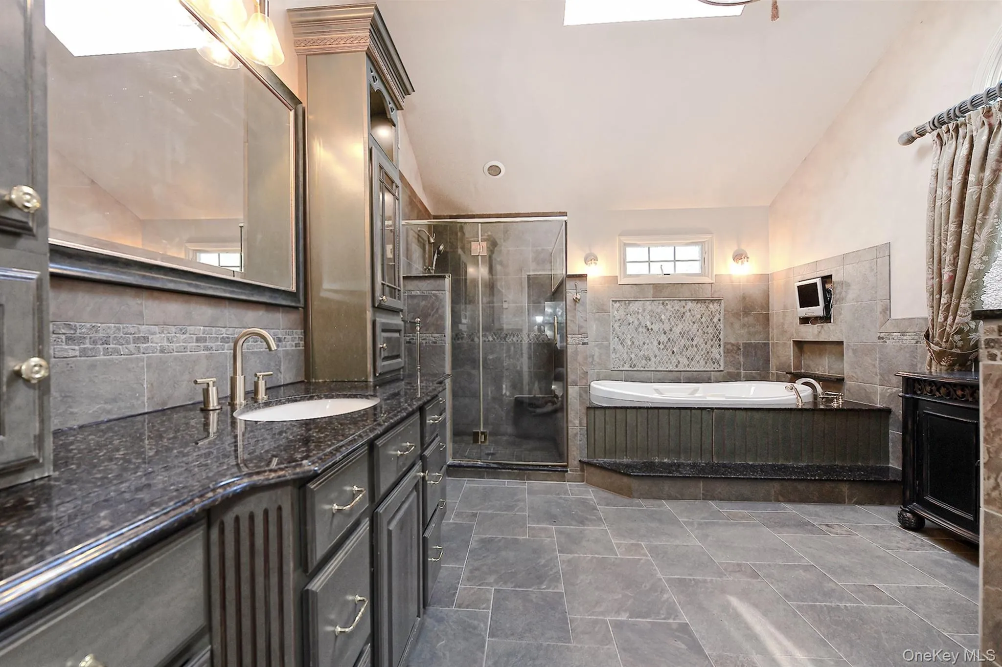 Bathroom featuring vanity, a garden tub, a shower stall, lofted ceiling, and tile walls Bathroom featuring vanity, a garden tub, a shower stall, lofted ceiling, and tile walls