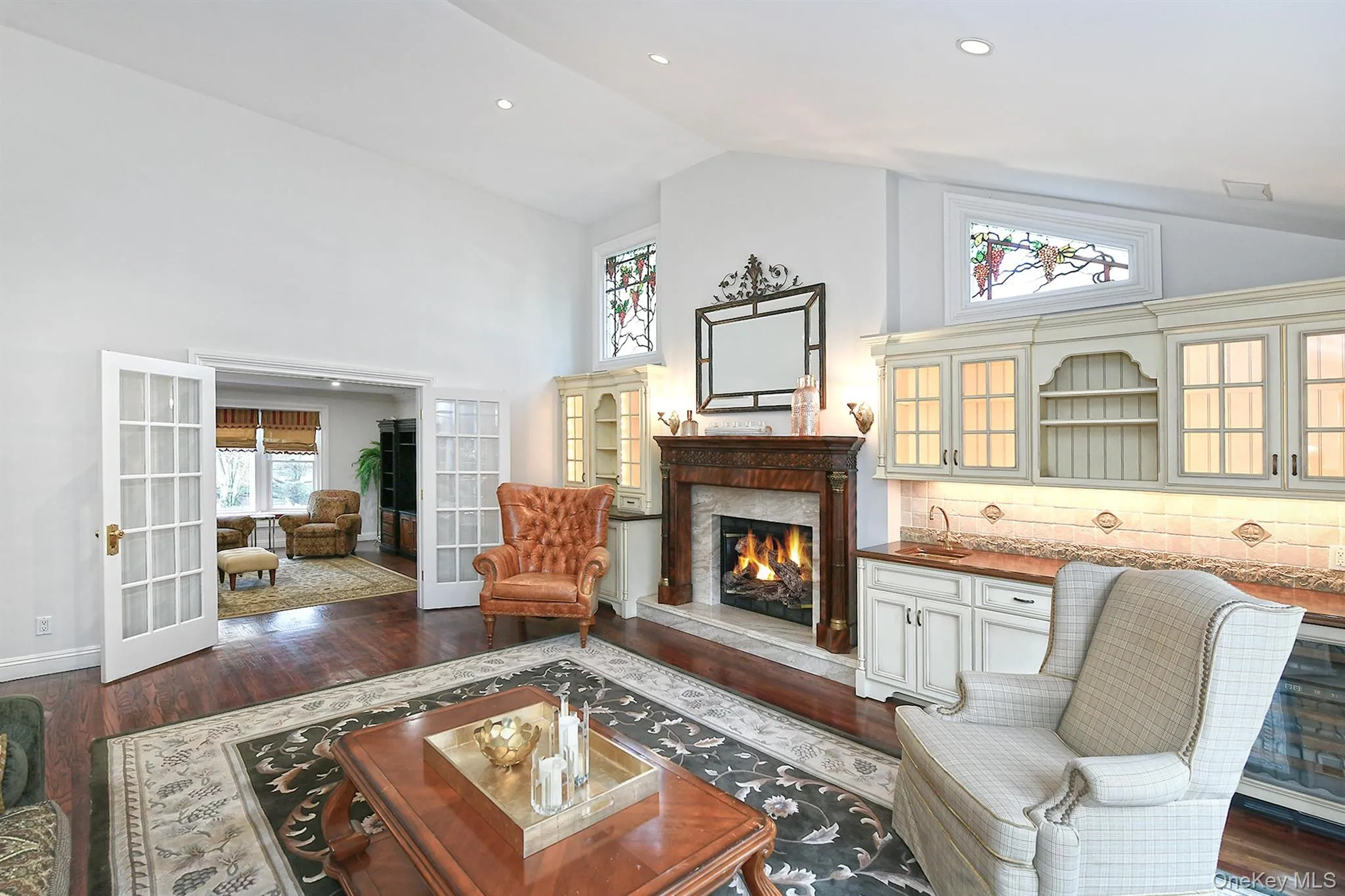 Living area featuring french doors, dark wood-type flooring, high vaulted ceiling, a high end fireplace, and recessed lighting Living area featuring french doors, dark wood-type flooring, high vaulted ceiling, a high end fireplace, and recessed lighting