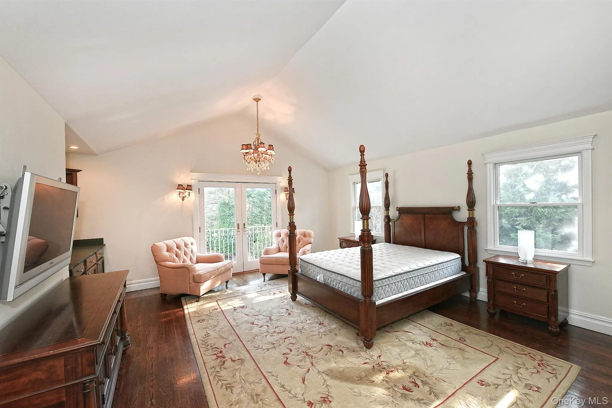 Bedroom featuring french doors, dark wood-type flooring, multiple windows, and lofted ceiling Bedroom featuring french doors, dark wood-type flooring, multiple windows, and lofted ceiling
