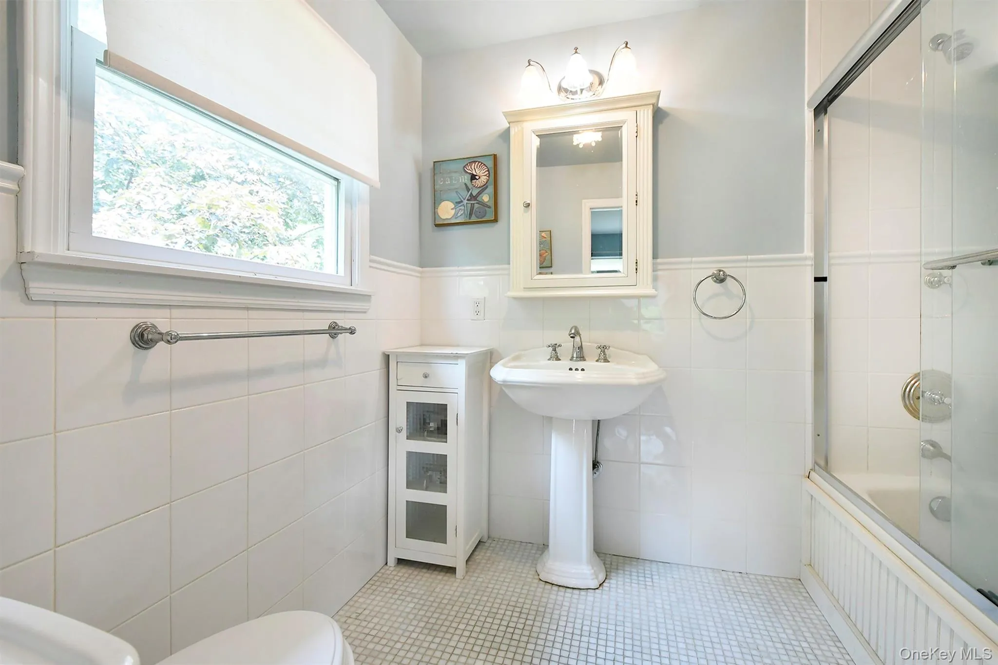 Full bathroom with tiled shower / bath, tile walls, light tile patterned floors, and wainscoting Full bathroom with tiled shower / bath, tile walls, light tile patterned floors, and wainscoting
