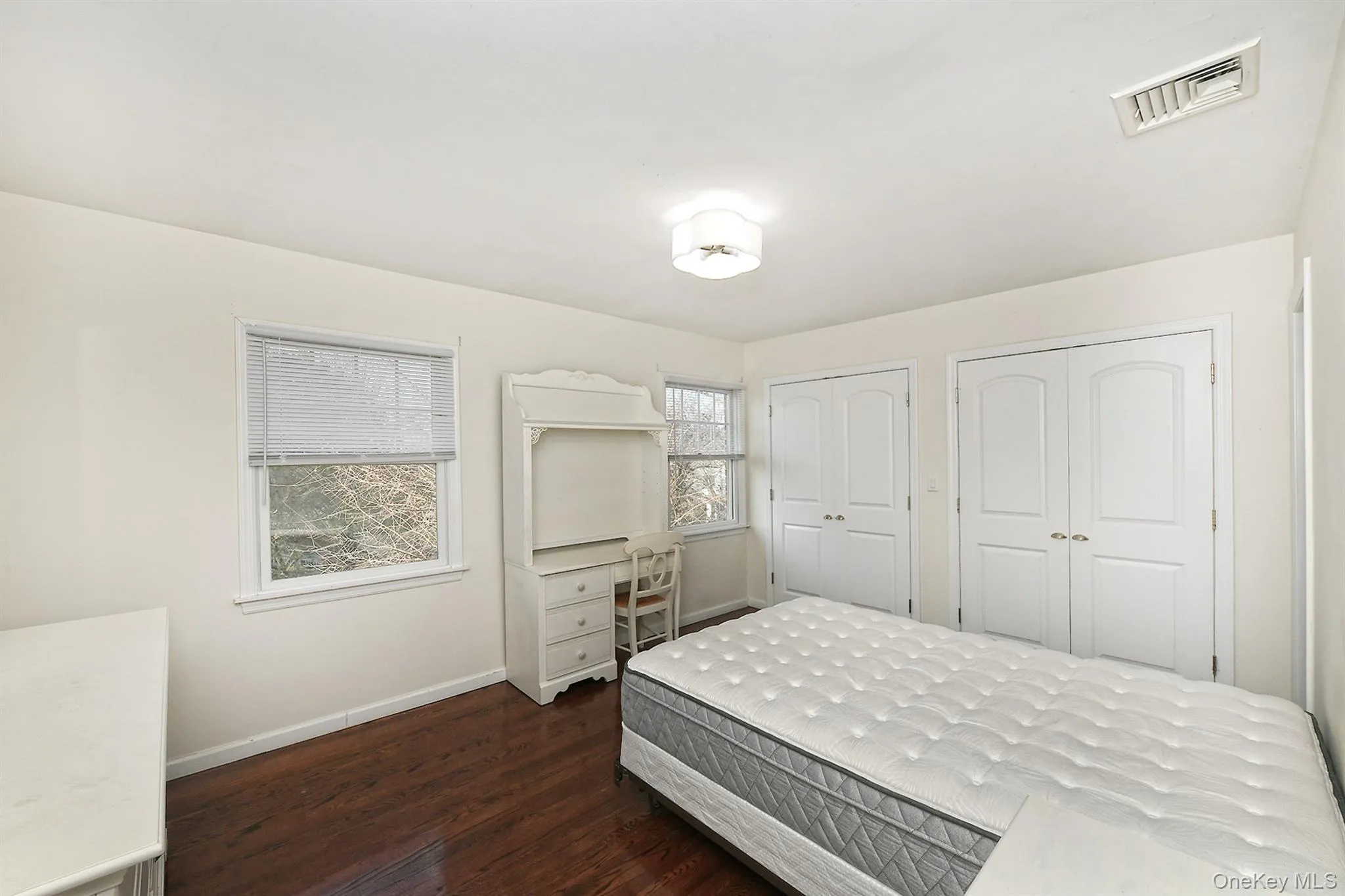 Bedroom featuring dark wood finished floors, multiple closets, and an office area Bedroom featuring dark wood finished floors, multiple closets, and an office area