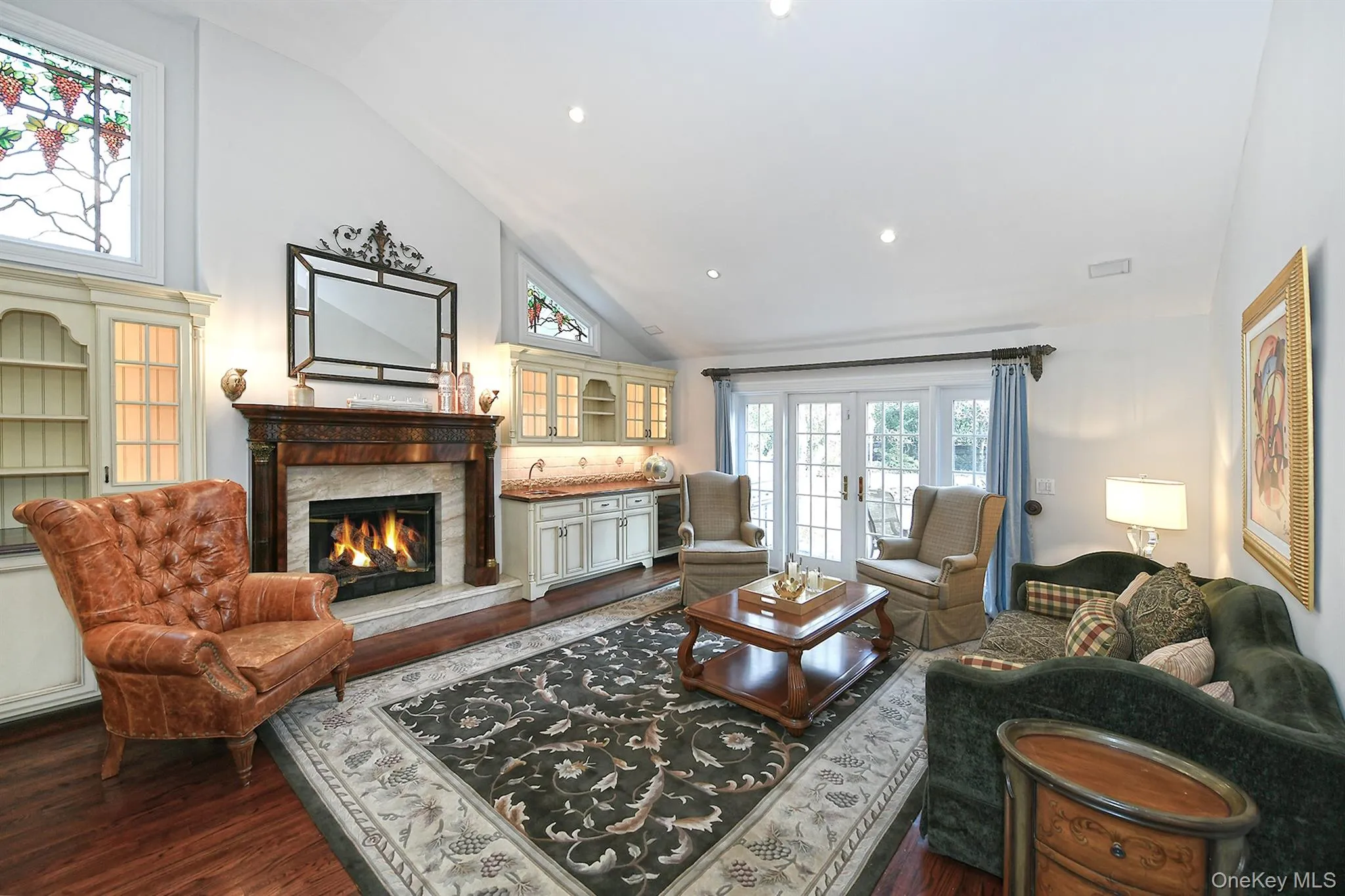 Living area with high vaulted ceiling, dark wood-style floors, a stone fireplace, and recessed lighting Living area with high vaulted ceiling, dark wood-style floors, a stone fireplace, and recessed lighting