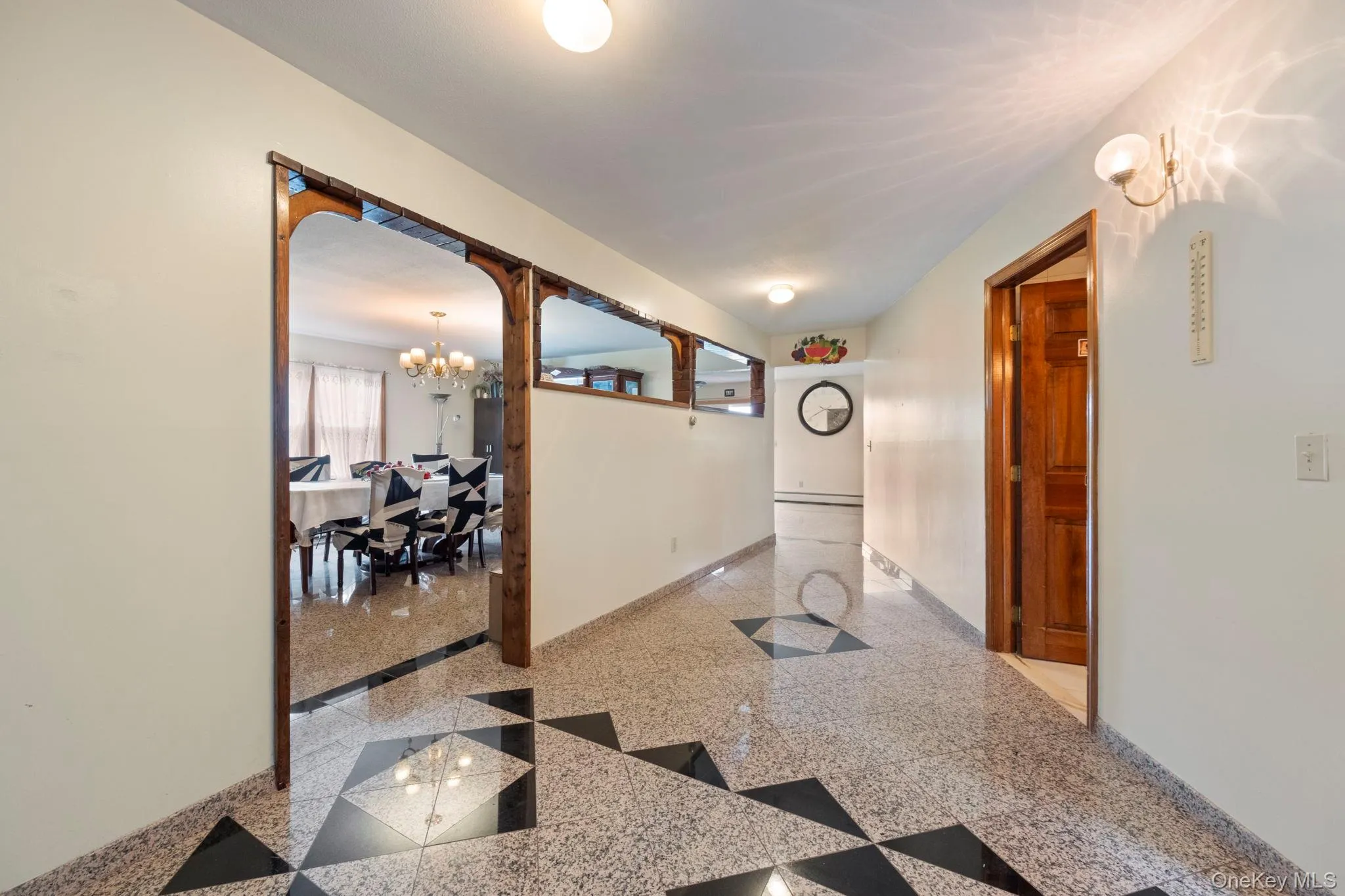 Hallway with a chandelier and granite tiled floors Hallway with a chandelier and granite tiled floors