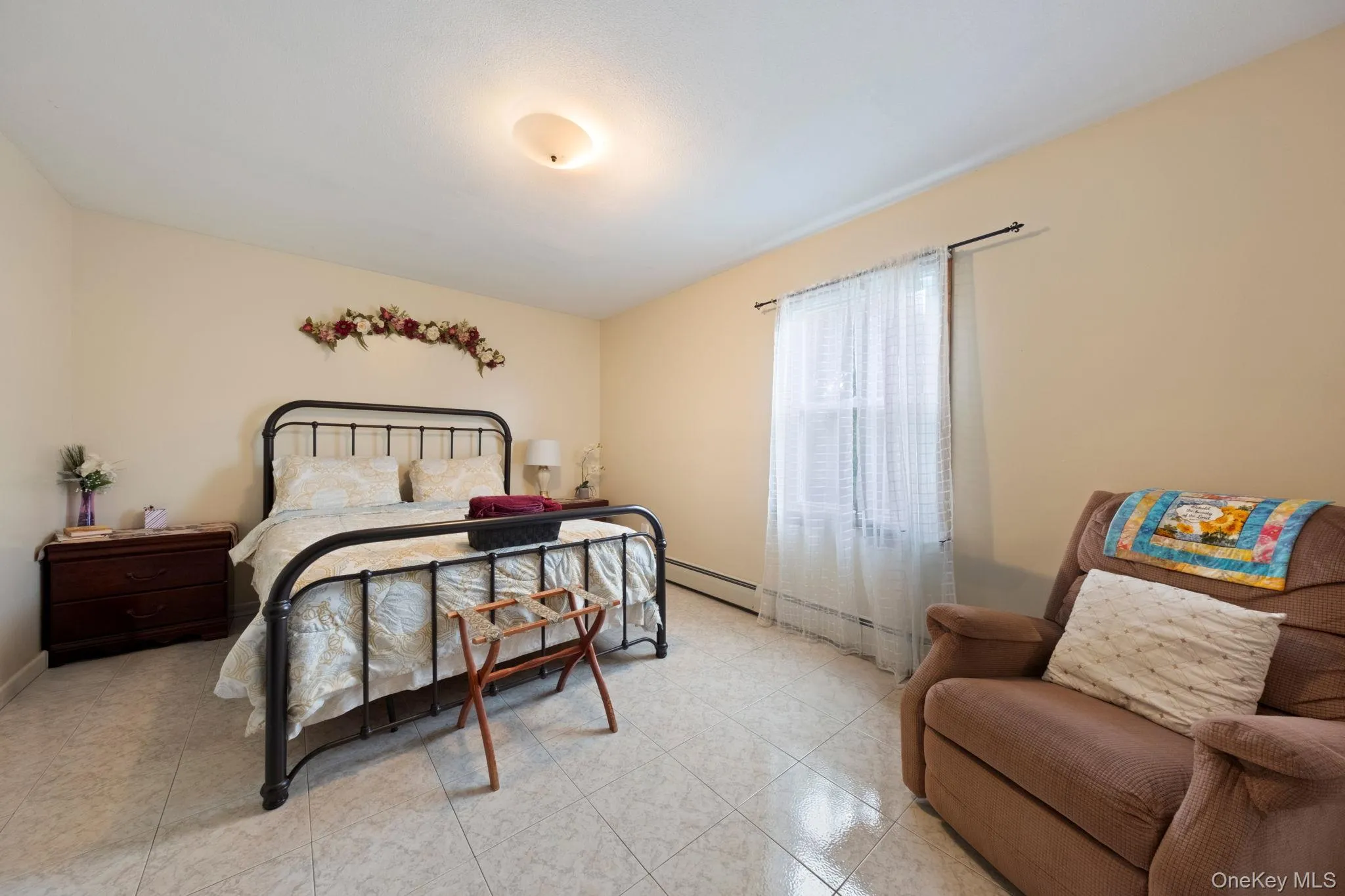 Bedroom featuring tile patterned flooring and a baseboard heating unit Bedroom featuring tile patterned flooring and a baseboard heating unit