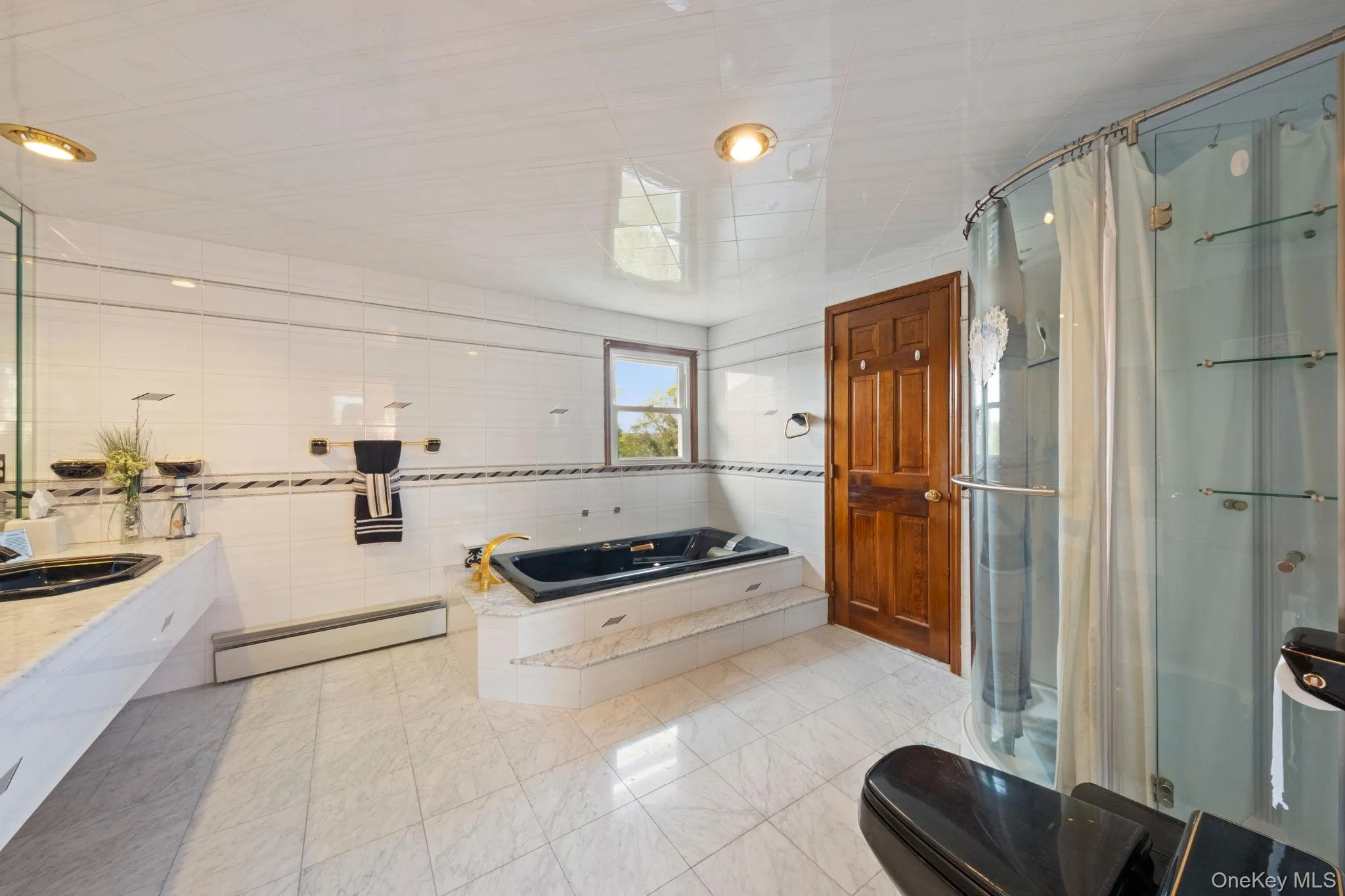 Bathroom with tile walls, a garden tub, a stall shower, a baseboard radiator, and light tile patterned flooring Bathroom with tile walls, a garden tub, a stall shower, a baseboard radiator, and light tile patterned flooring