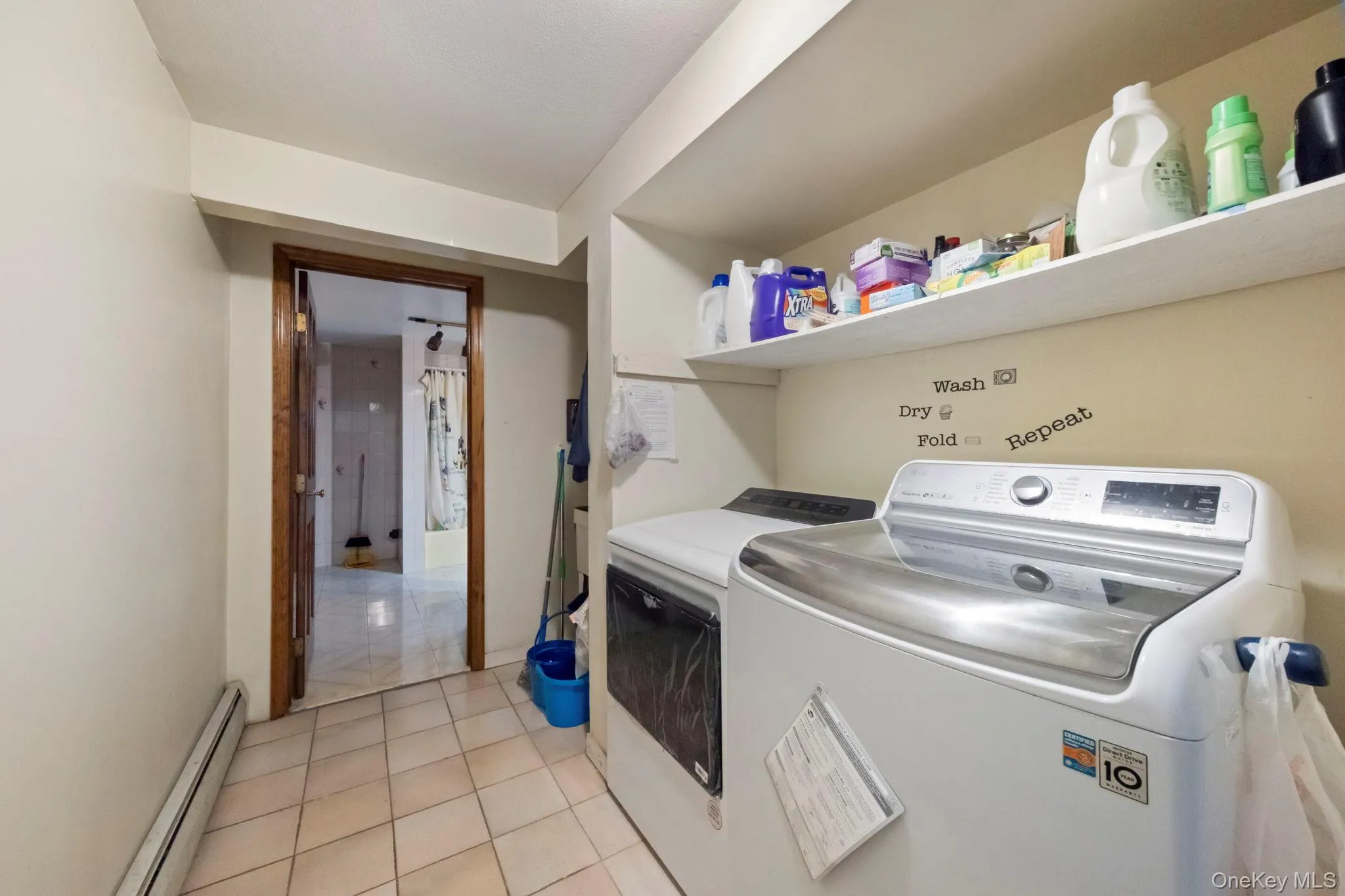 Laundry area featuring light tile patterned floors, a baseboard heating unit, and independent washer and dryer Laundry area featuring light tile patterned floors, a baseboard heating unit, and independent washer and dryer