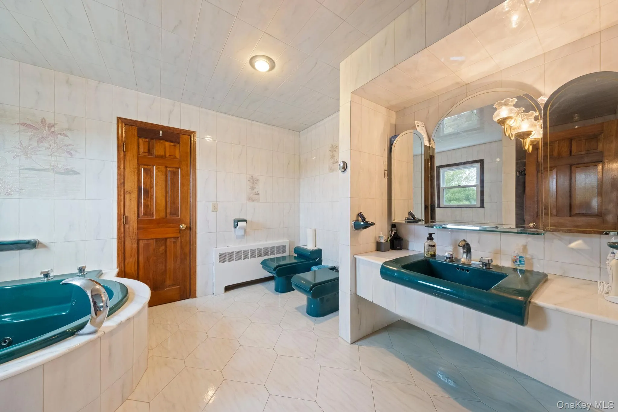 Full bath with tile walls, radiator, a jetted tub, a chandelier, and vanity Full bath with tile walls, radiator, a jetted tub, a chandelier, and vanity