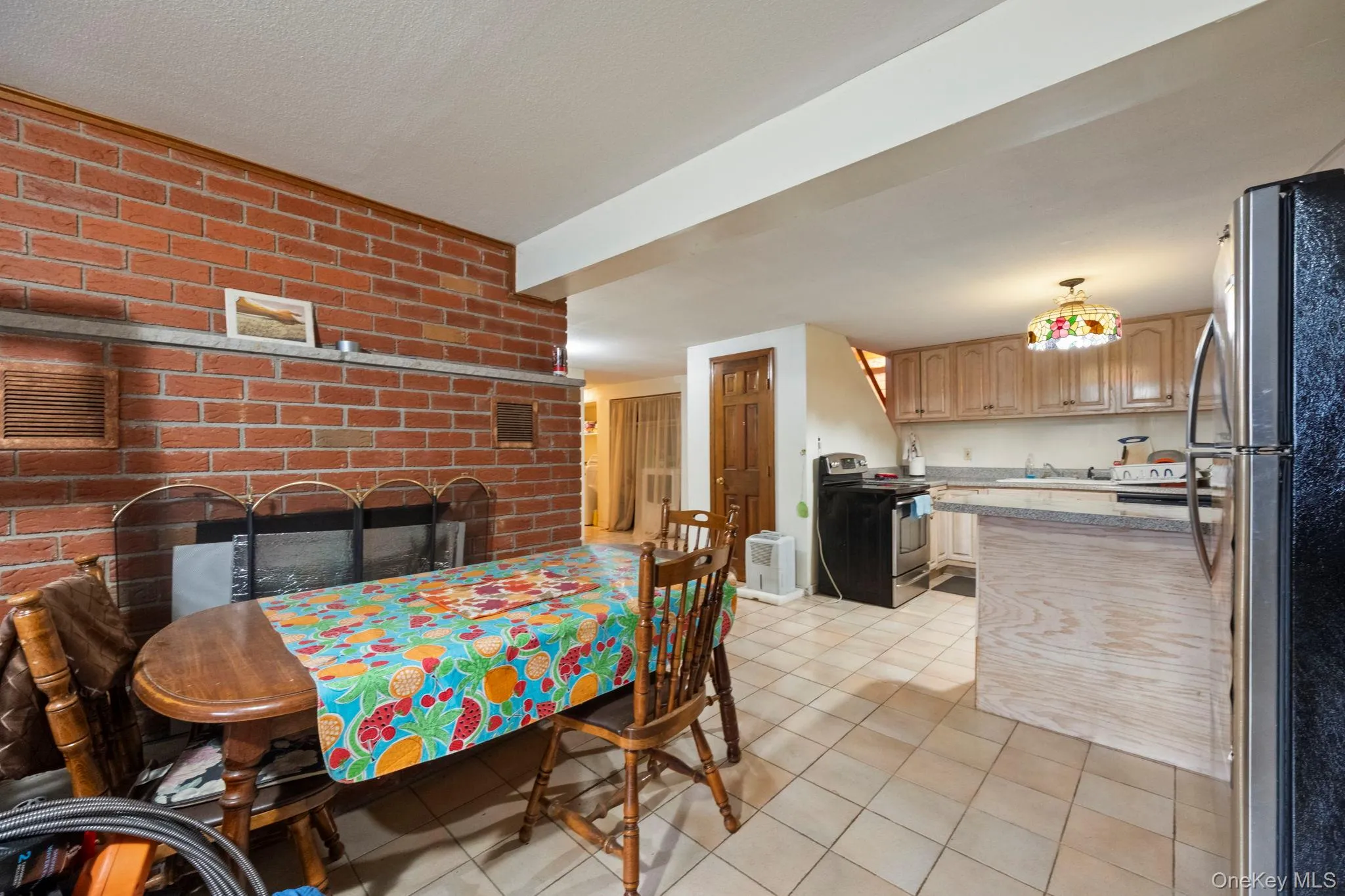 Dining area with light tile patterned floors, a fireplace, and brick wall Dining area with light tile patterned floors, a fireplace, and brick wall