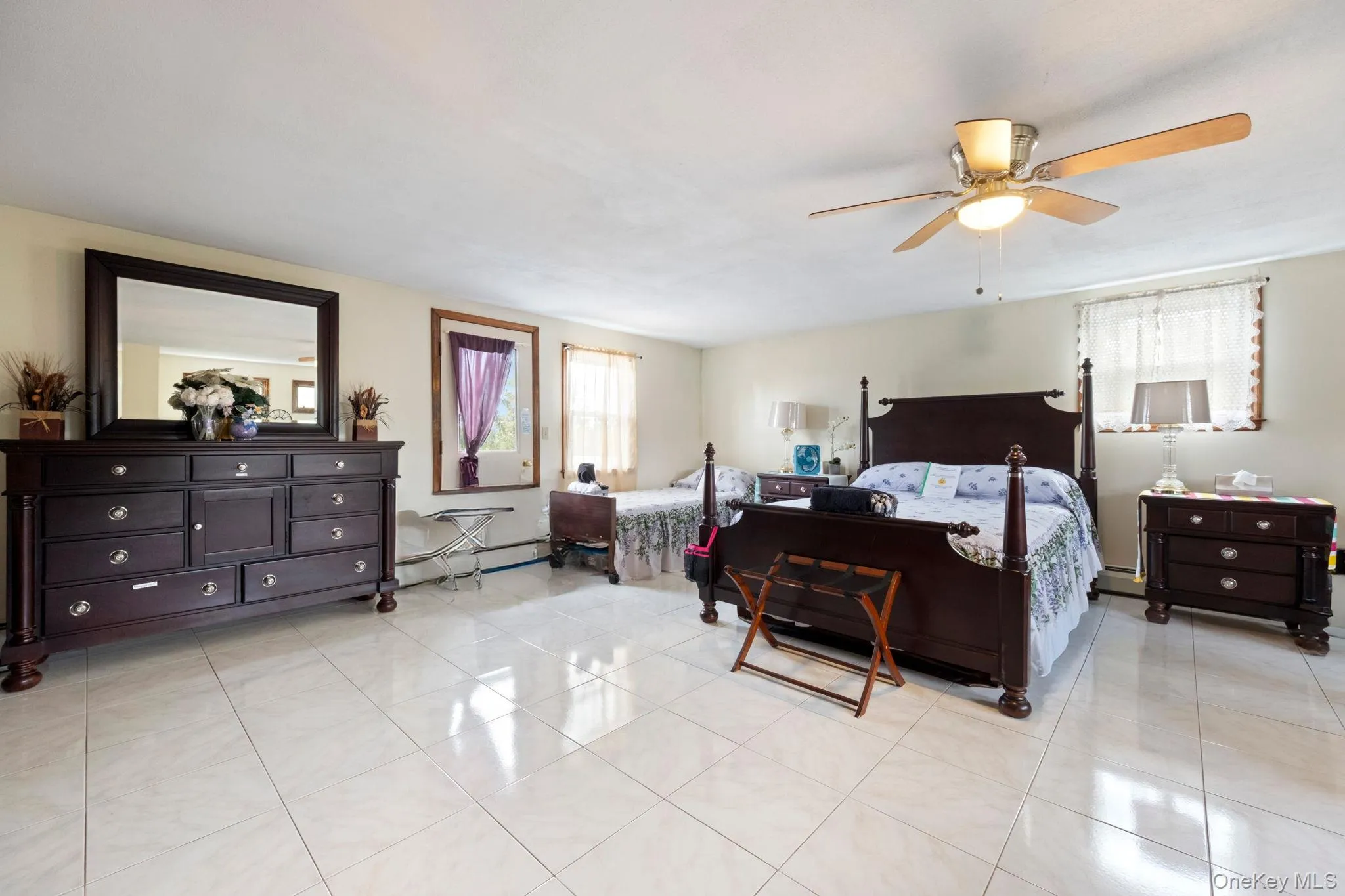 Bedroom featuring light tile patterned flooring, a baseboard heating unit, and ceiling fan Bedroom featuring light tile patterned flooring, a baseboard heating unit, and ceiling fan
