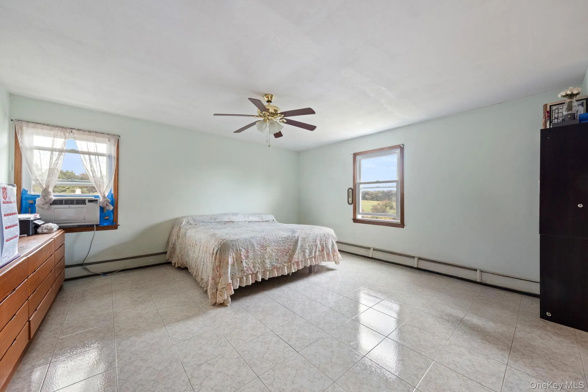 Bedroom featuring a baseboard heating unit, a ceiling fan, light tile patterned floors, and cooling unit Bedroom featuring a baseboard heating unit, a ceiling fan, light tile patterned floors, and cooling unit
