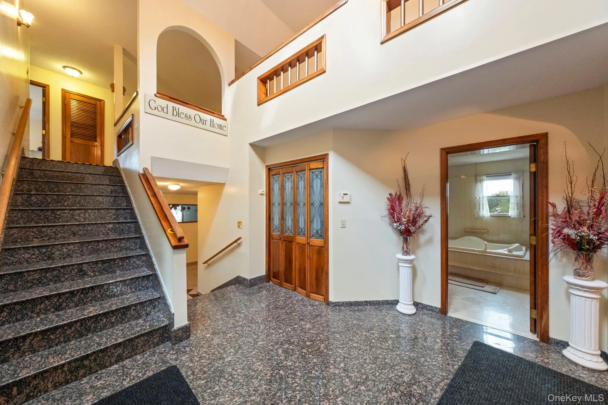 Entryway with granite floors, stairs, and a high ceiling Entryway with granite floors, stairs, and a high ceiling