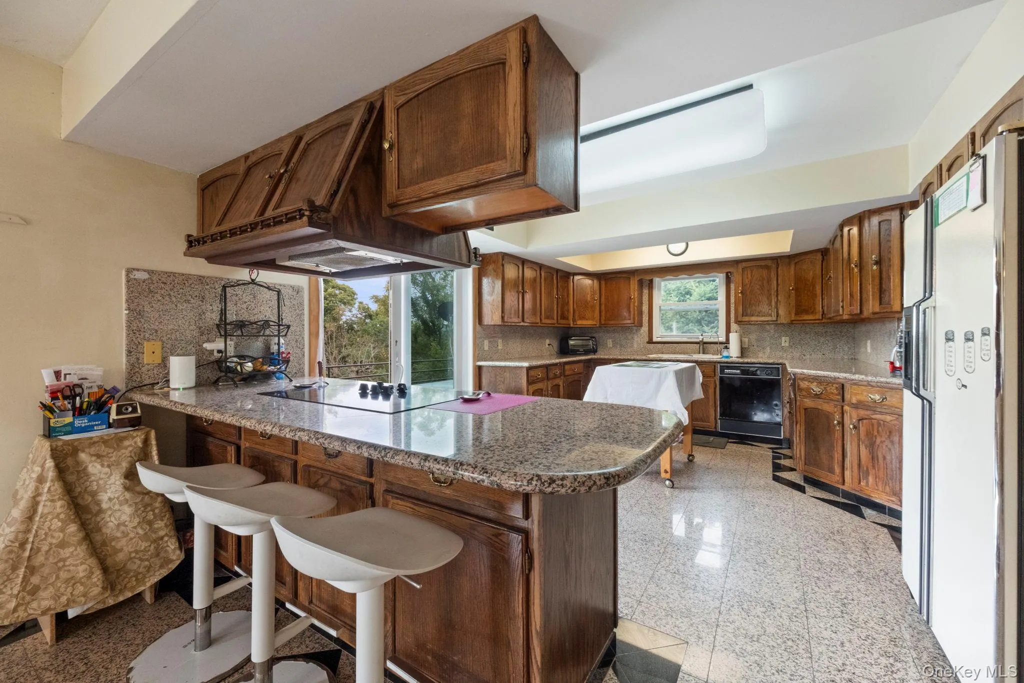 Kitchen featuring granite floors, a peninsula, black appliances, backsplash, and a breakfast bar area Kitchen featuring granite floors, a peninsula, black appliances, backsplash, and a breakfast bar area